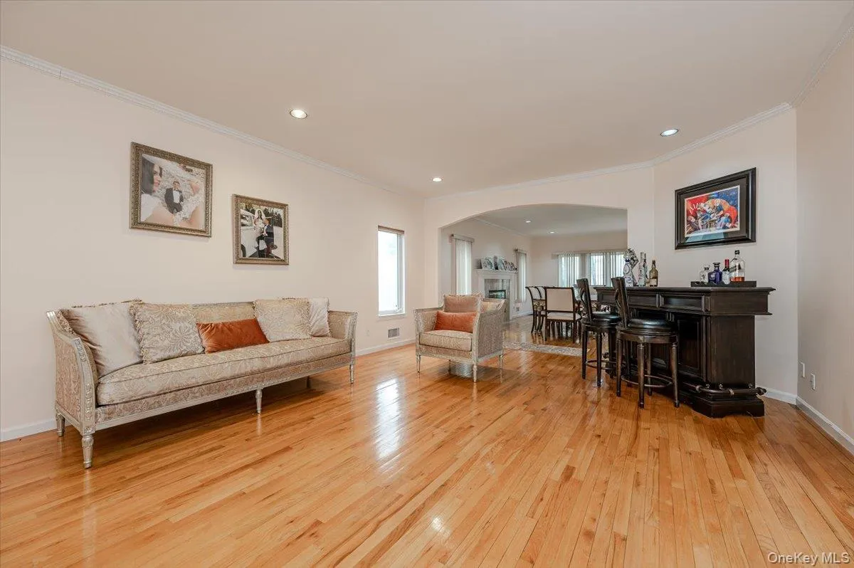 Living area featuring a dry bar, light wood-type flooring, crown molding, recessed lighting, and arched walkways Living area featuring a dry bar, light wood-type flooring, crown molding, recessed lighting, and arched walkways