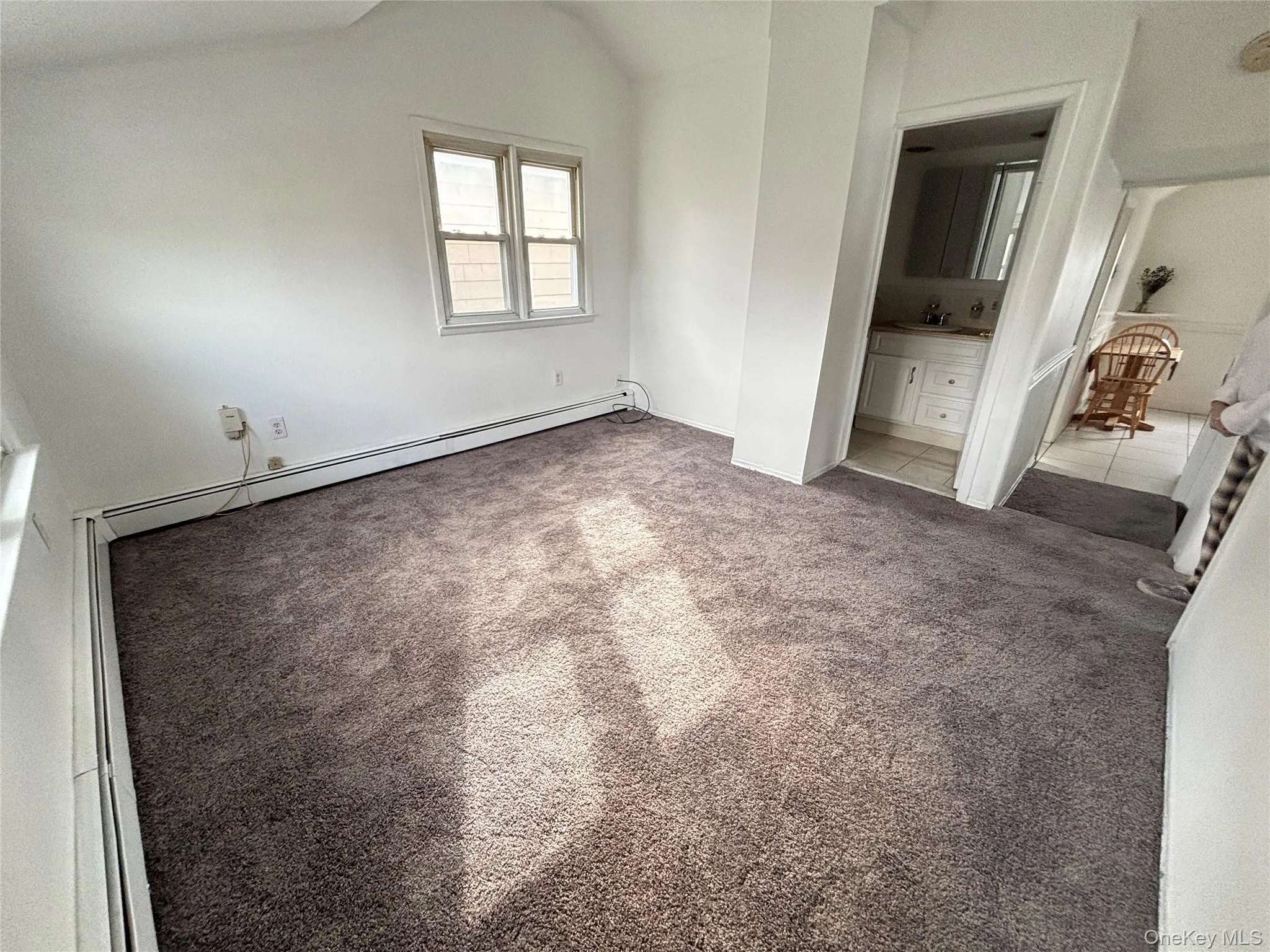 Unfurnished bedroom featuring vaulted ceiling, carpet flooring, ensuite bath, a baseboard heating unit, and baseboard heating Unfurnished bedroom featuring vaulted ceiling, carpet flooring, ensuite bath, a baseboard heating unit, and baseboard heating