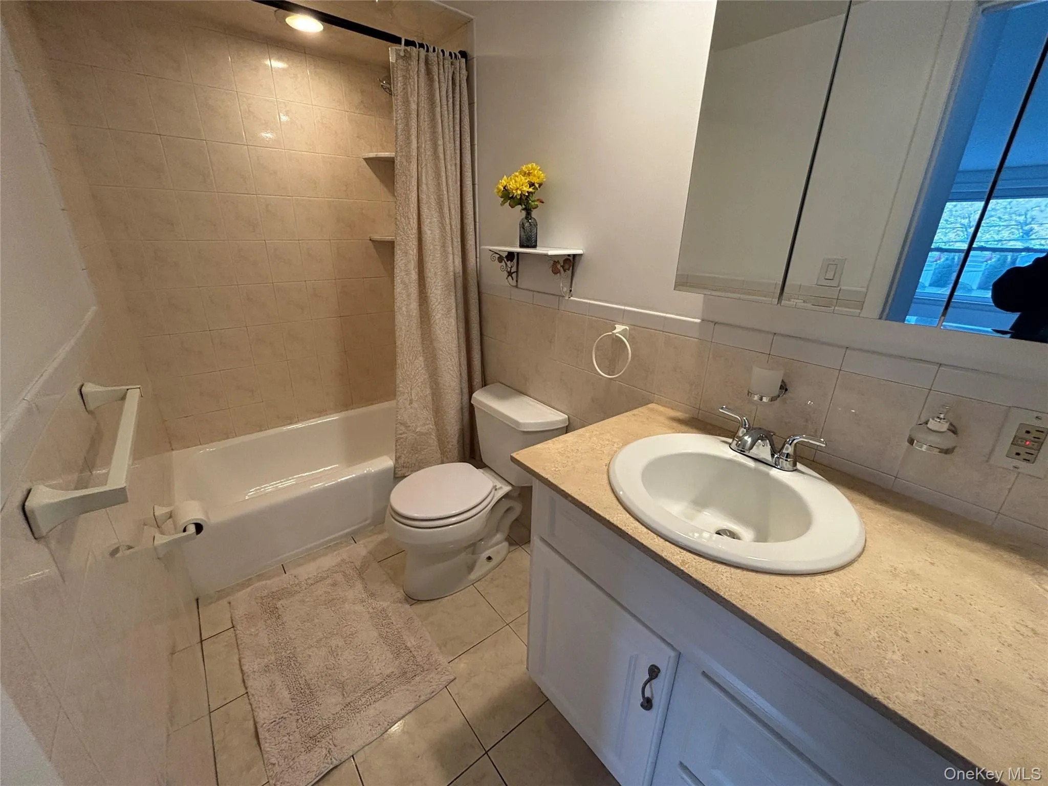 Bathroom with vanity, tile walls, shower / bath combo, light tile patterned flooring, and backsplash Bathroom with vanity, tile walls, shower / bath combo, light tile patterned flooring, and backsplash