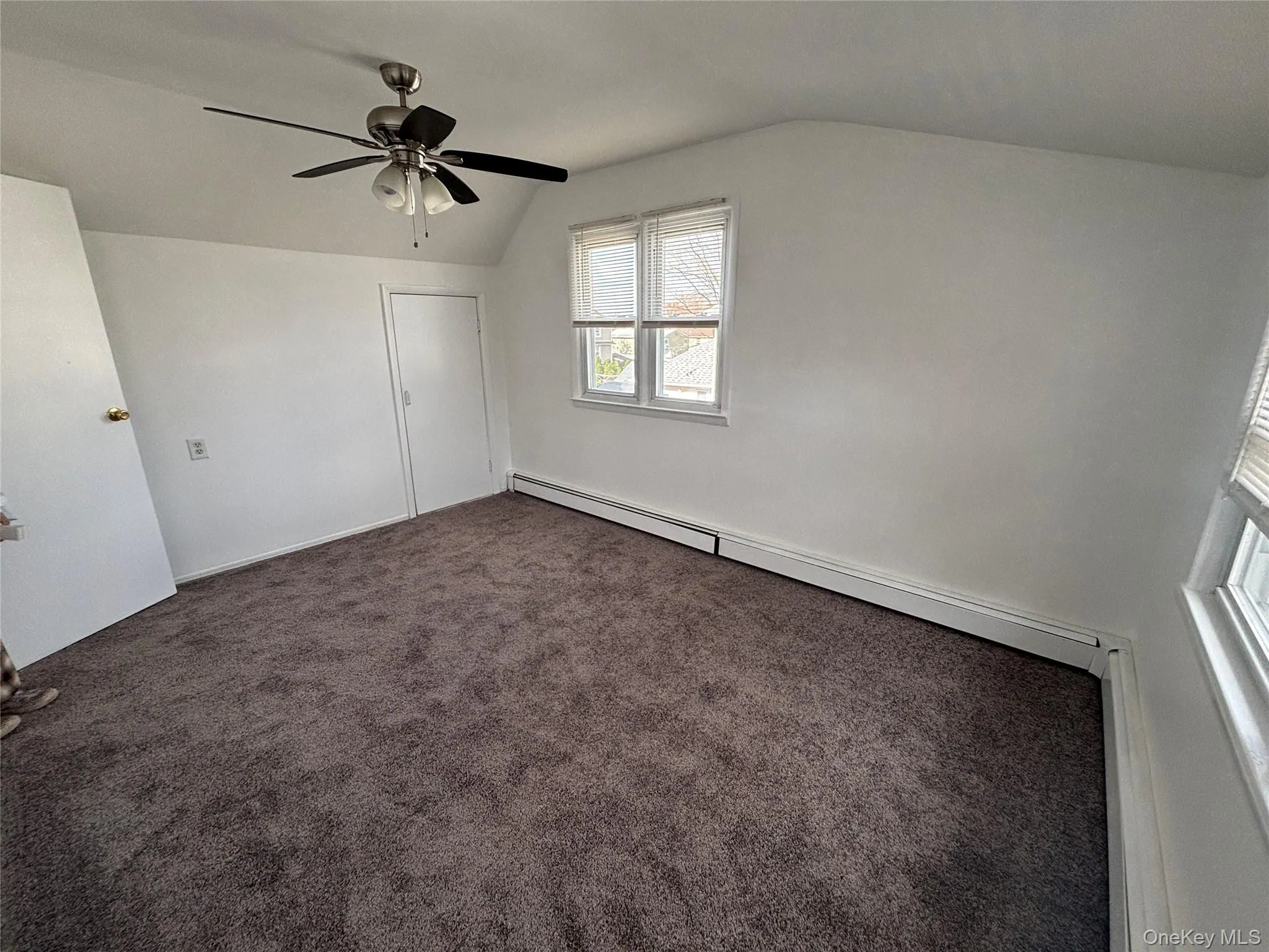 Bonus room with vaulted ceiling, a baseboard heating unit, and dark colored carpet Bonus room with vaulted ceiling, a baseboard heating unit, and dark colored carpet
