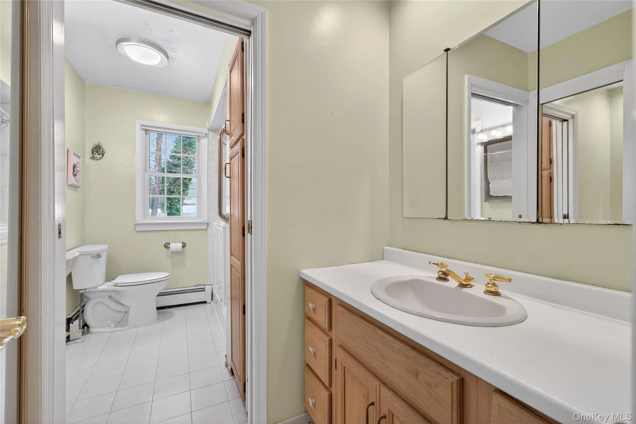 Bathroom with vanity, baseboard heating, and light tile patterned flooring Bathroom with vanity, baseboard heating, and light tile patterned flooring