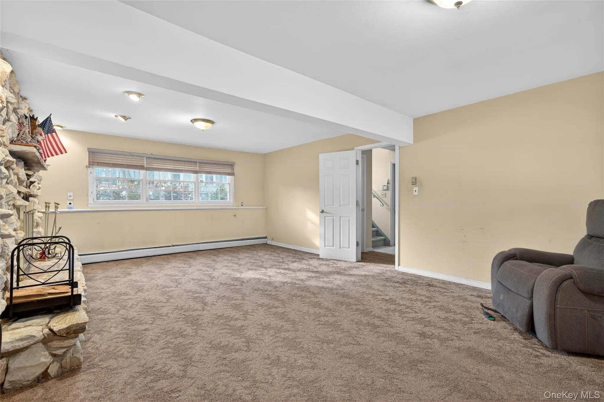 Sitting room featuring a baseboard heating unit, stairway, and carpet Sitting room featuring a baseboard heating unit, stairway, and carpet