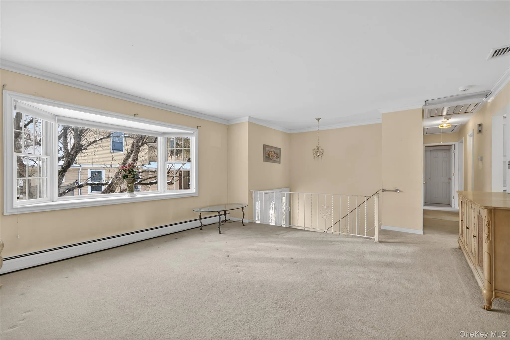 Spare room featuring attic access, baseboard heating, ornamental molding, and light carpet Spare room featuring attic access, baseboard heating, ornamental molding, and light carpet