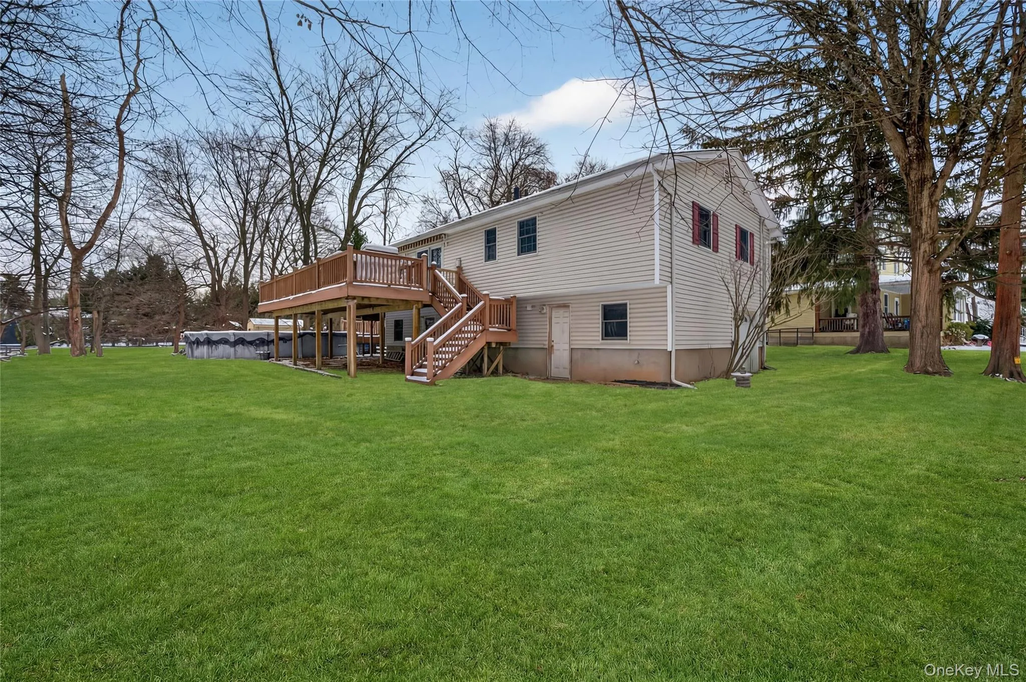 Back of property featuring stairs, a covered pool, a lawn, and a wooden deck Back of property featuring stairs, a covered pool, a lawn, and a wooden deck
