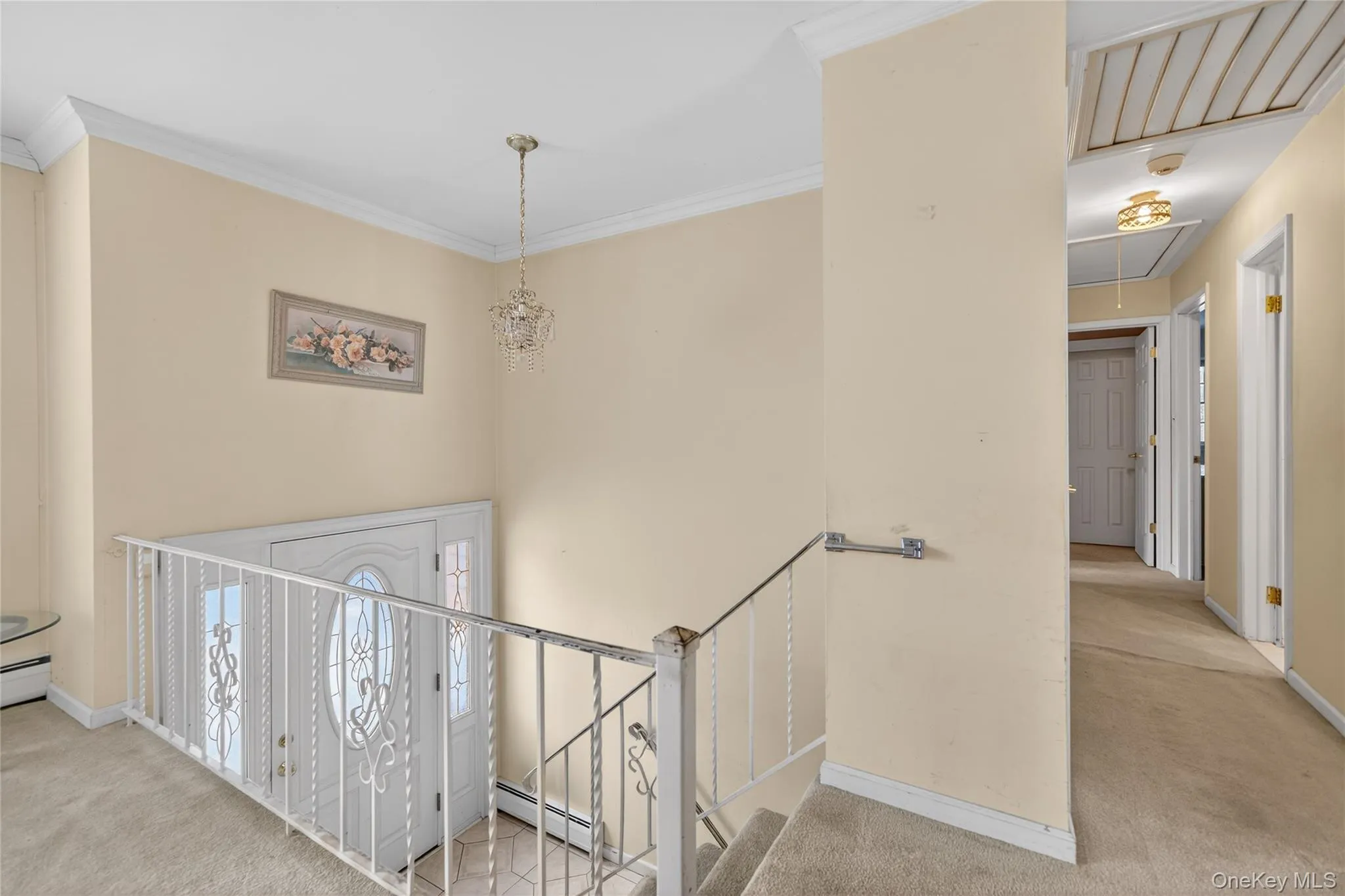 Hall with attic access, light colored carpet, a baseboard heating unit, a chandelier, and an upstairs landing Hall with attic access, light colored carpet, a baseboard heating unit, a chandelier, and an upstairs landing