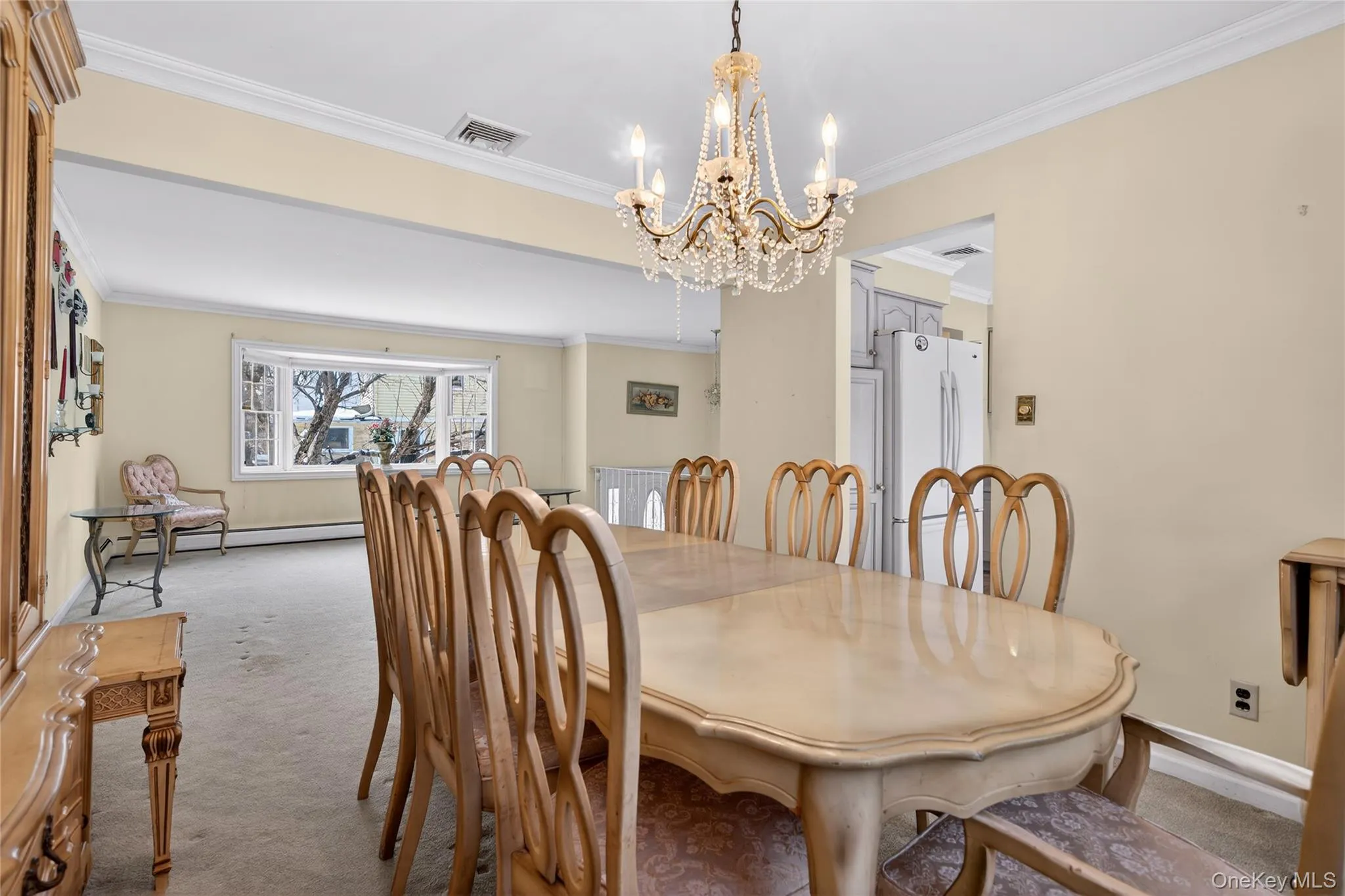 Carpeted dining space with ornamental molding, a chandelier, and baseboard heating Carpeted dining space with ornamental molding, a chandelier, and baseboard heating