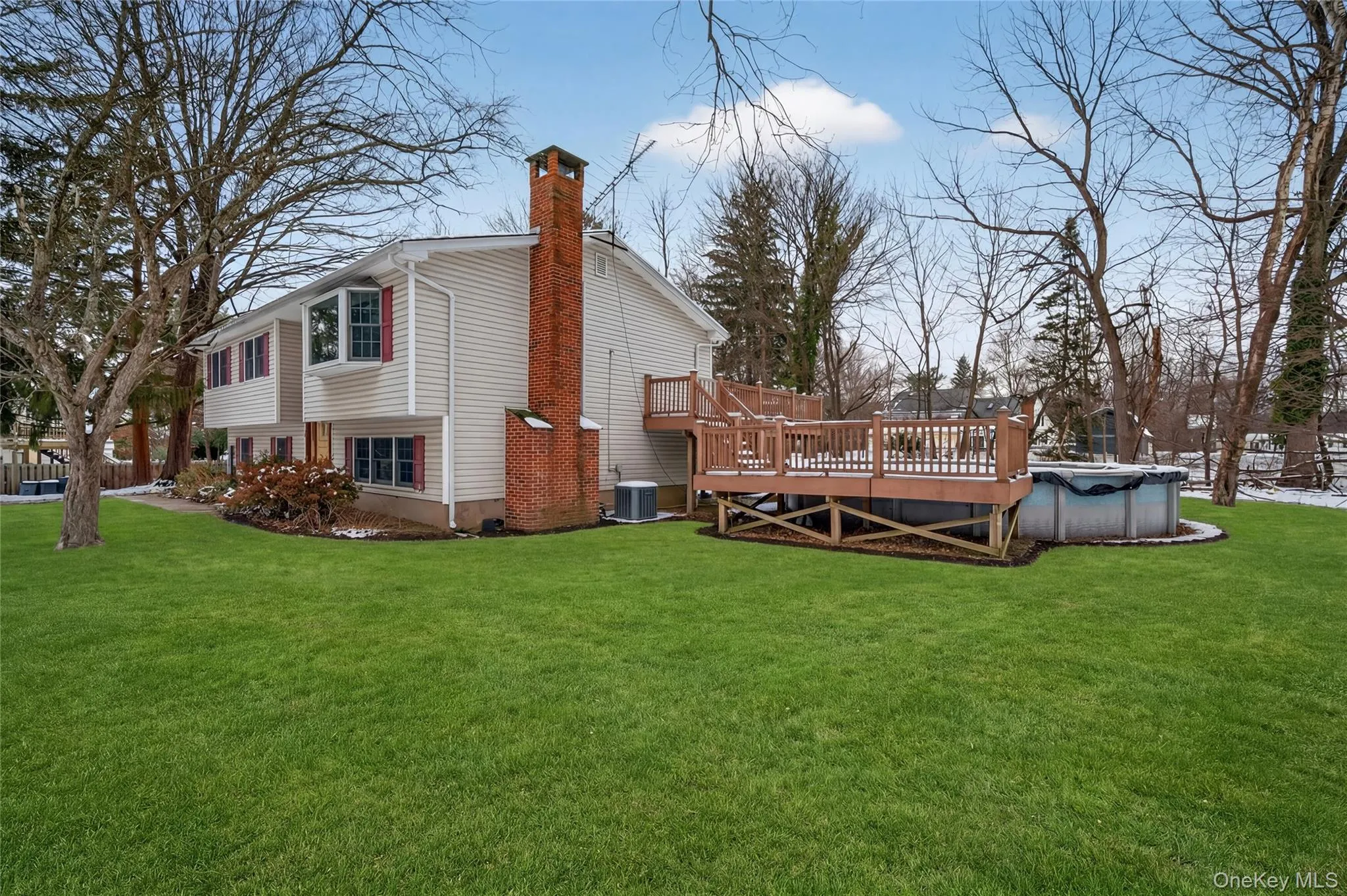 View of side of property with a yard, a wooden deck, a chimney, and a covered pool View of side of property with a yard, a wooden deck, a chimney, and a covered pool