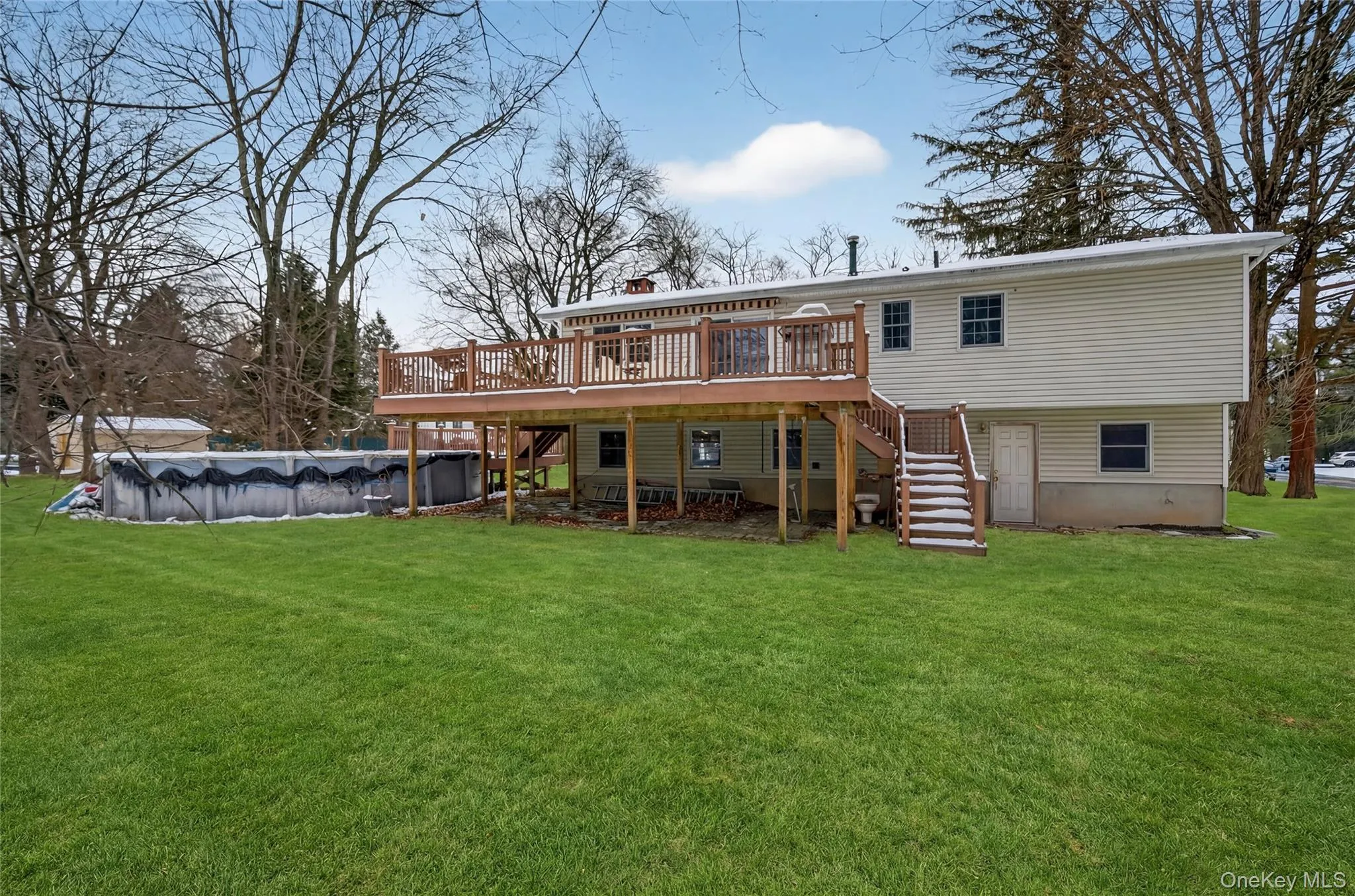 Rear view of property featuring stairs, a deck, a covered pool, a lawn, and a chimney Rear view of property featuring stairs, a deck, a covered pool, a lawn, and a chimney