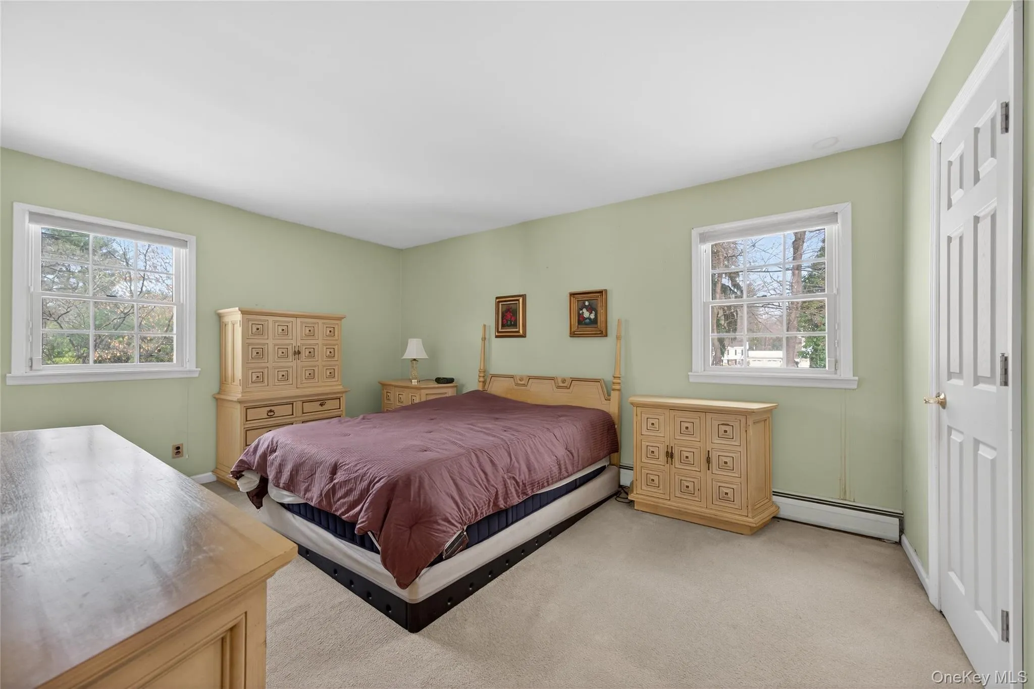 Carpeted bedroom with baseboard heating and multiple windows Carpeted bedroom with baseboard heating and multiple windows