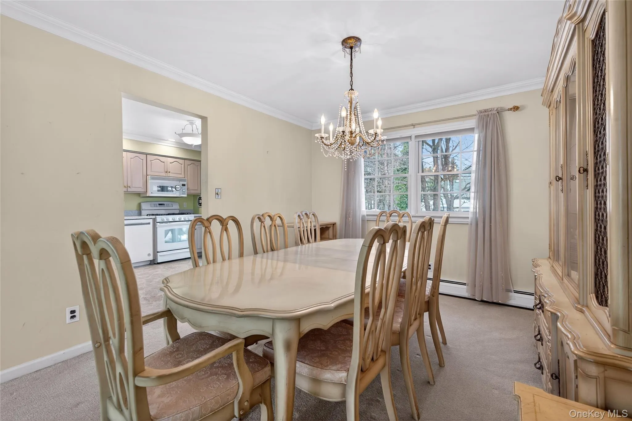 Dining room with ornamental molding, a chandelier, and light colored carpet Dining room with ornamental molding, a chandelier, and light colored carpet