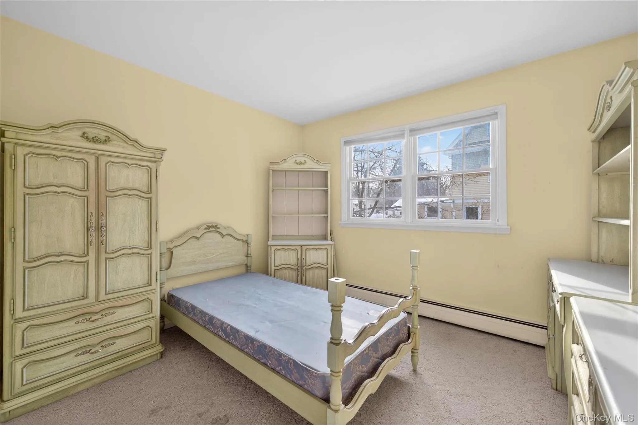 Bedroom with light colored carpet and a baseboard radiator Bedroom with light colored carpet and a baseboard radiator