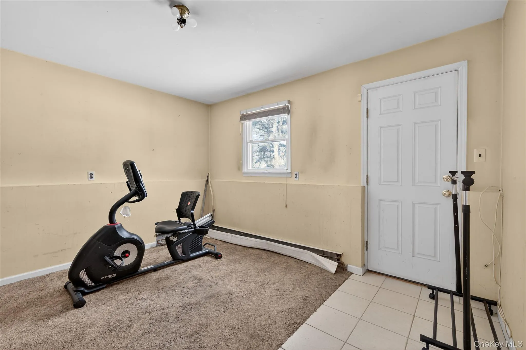 Exercise room featuring a baseboard heating unit, tile patterned floors, and carpet Exercise room featuring a baseboard heating unit, tile patterned floors, and carpet
