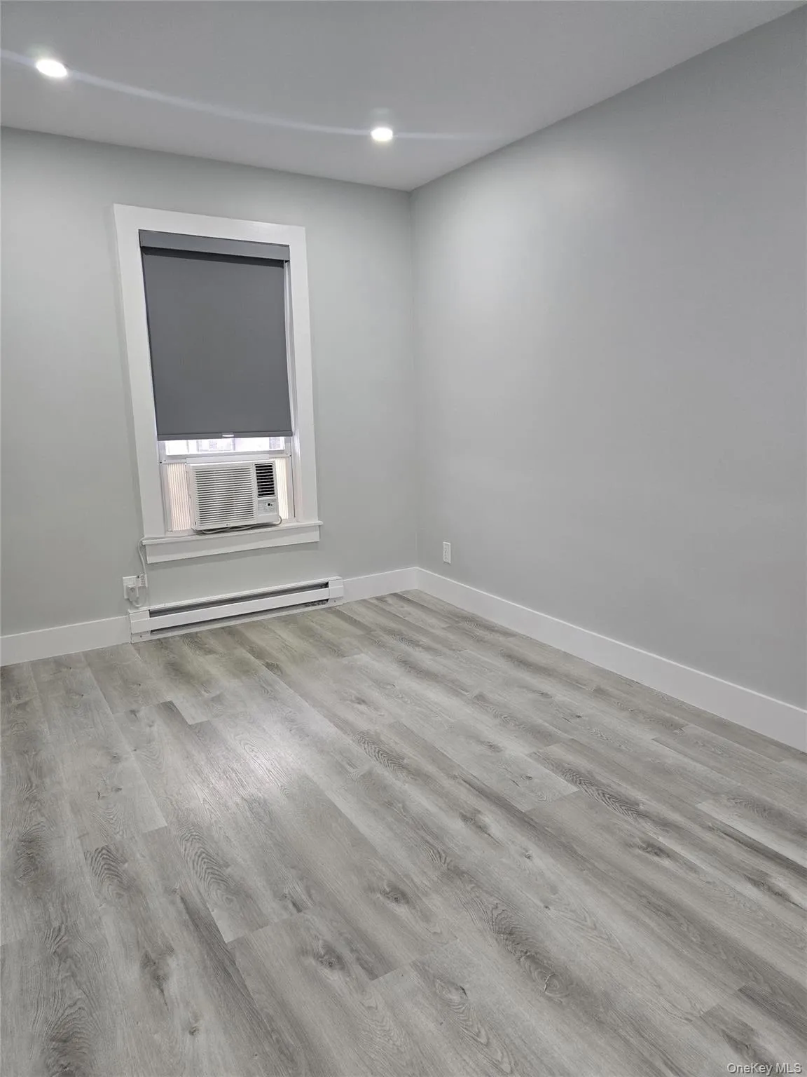 Unfurnished room featuring light wood-style flooring, a baseboard heating unit, and recessed lighting Unfurnished room featuring light wood-style flooring, a baseboard heating unit, and recessed lighting