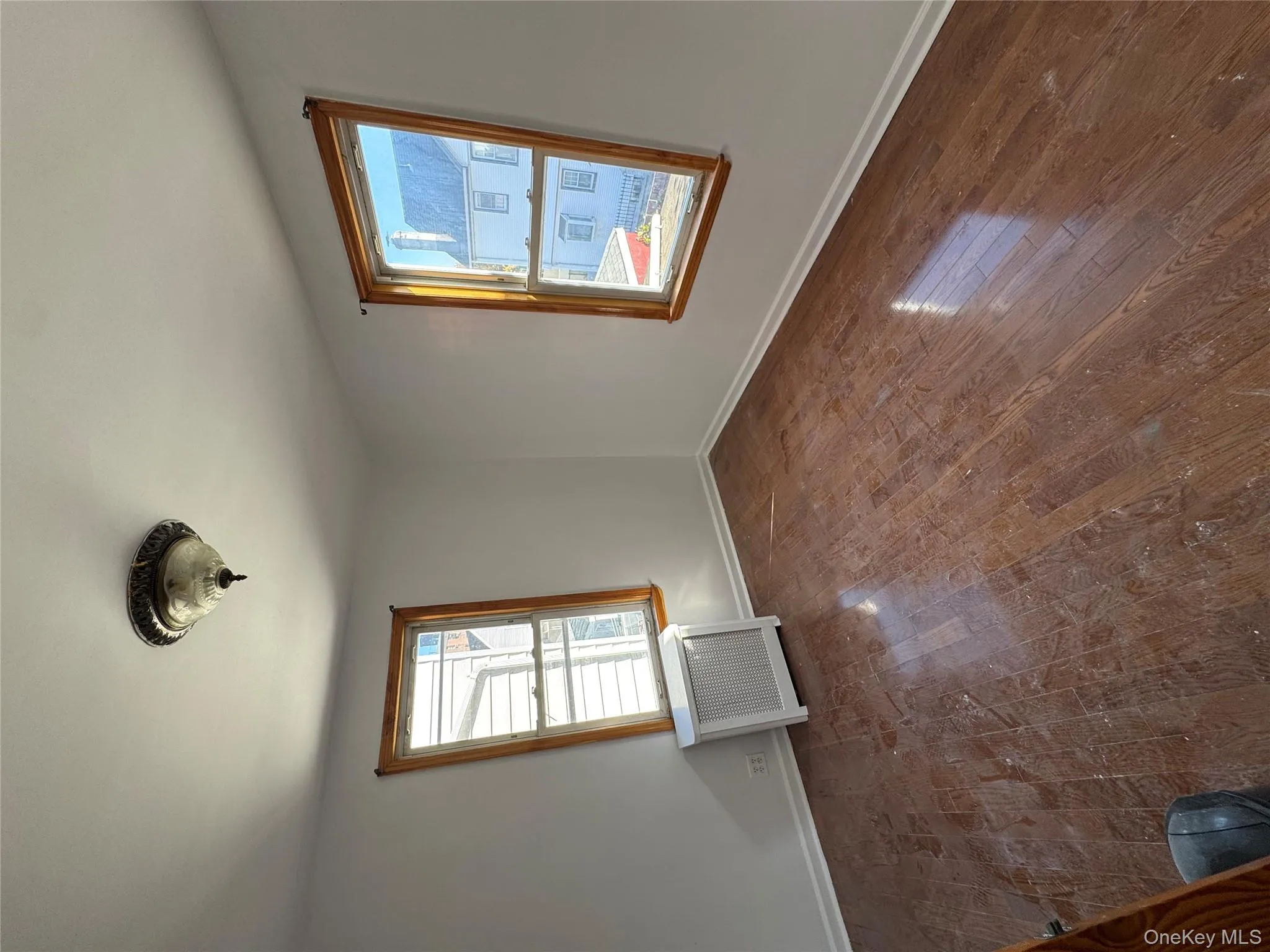 Empty room featuring dark wood-type flooring, radiator, and healthy amount of natural light Empty room featuring dark wood-type flooring, radiator, and healthy amount of natural light