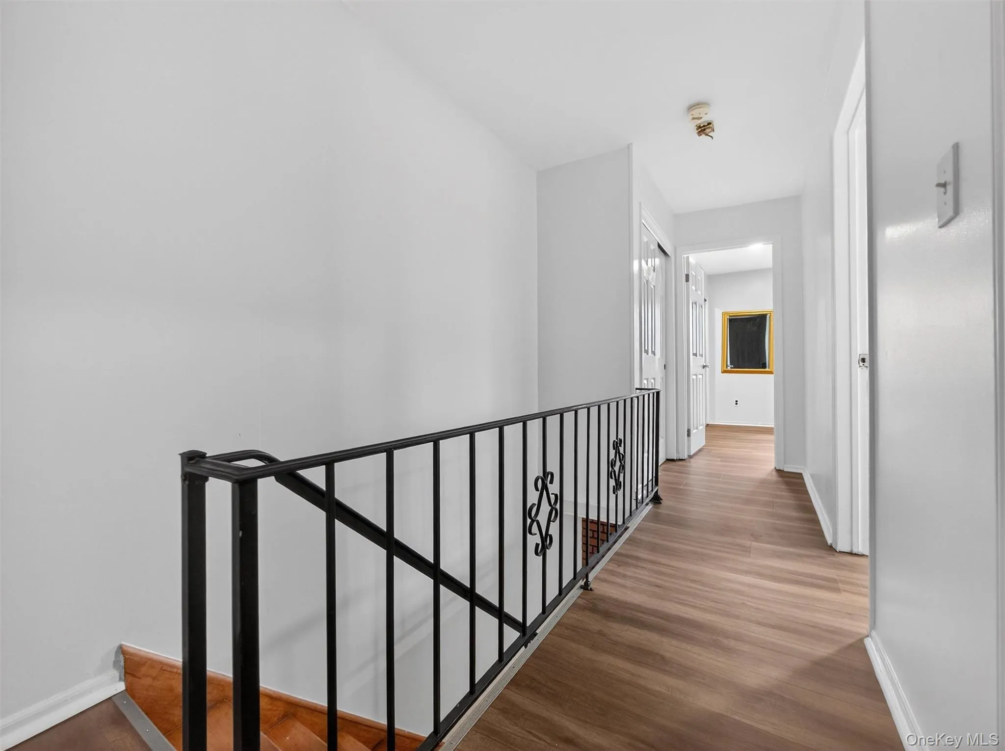 Hallway with an upstairs landing and dark wood-type flooring Hallway with an upstairs landing and dark wood-type flooring