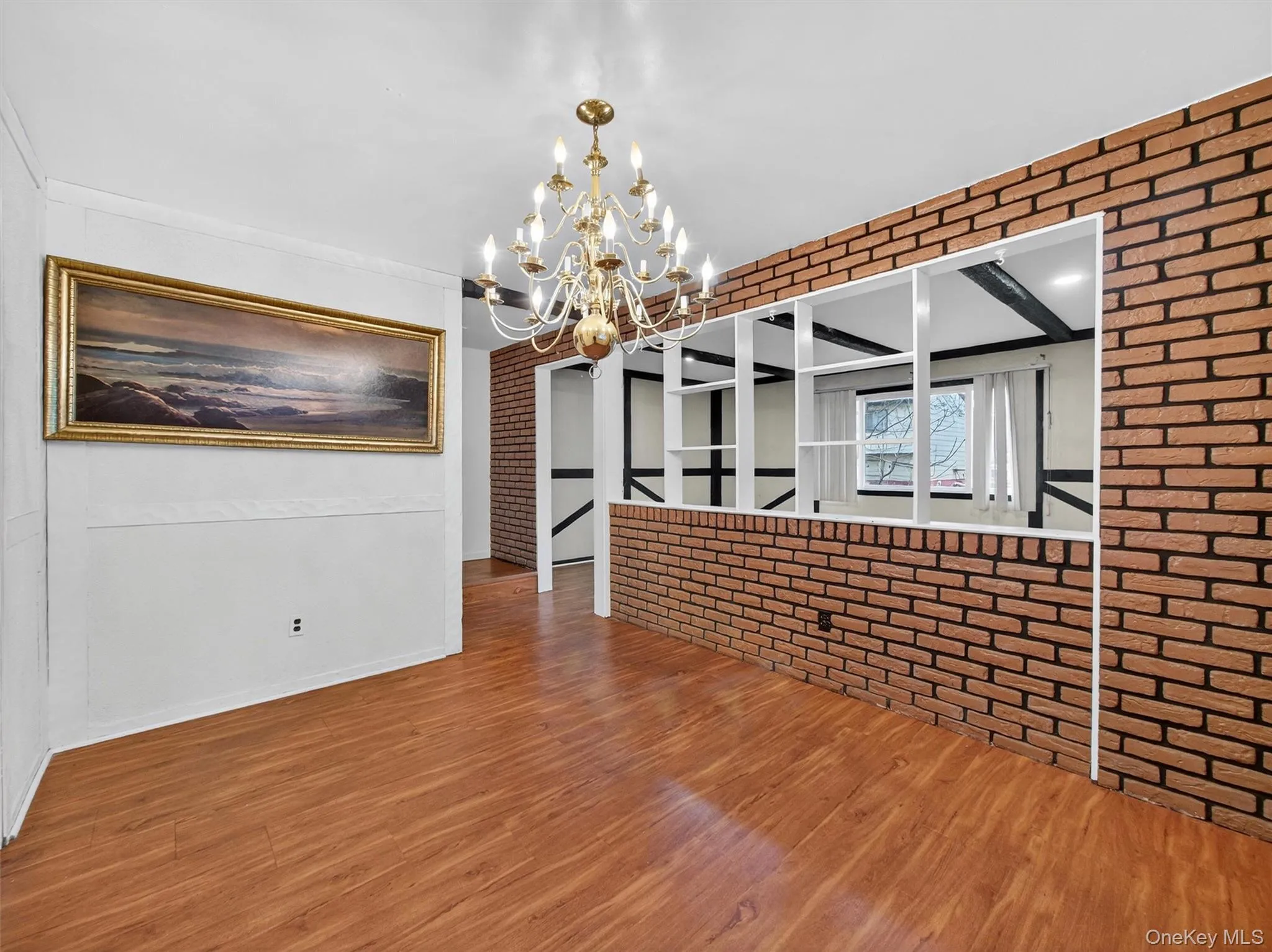 Unfurnished dining area featuring brick wall, wood finished floors, and a chandelier Unfurnished dining area featuring brick wall, wood finished floors, and a chandelier