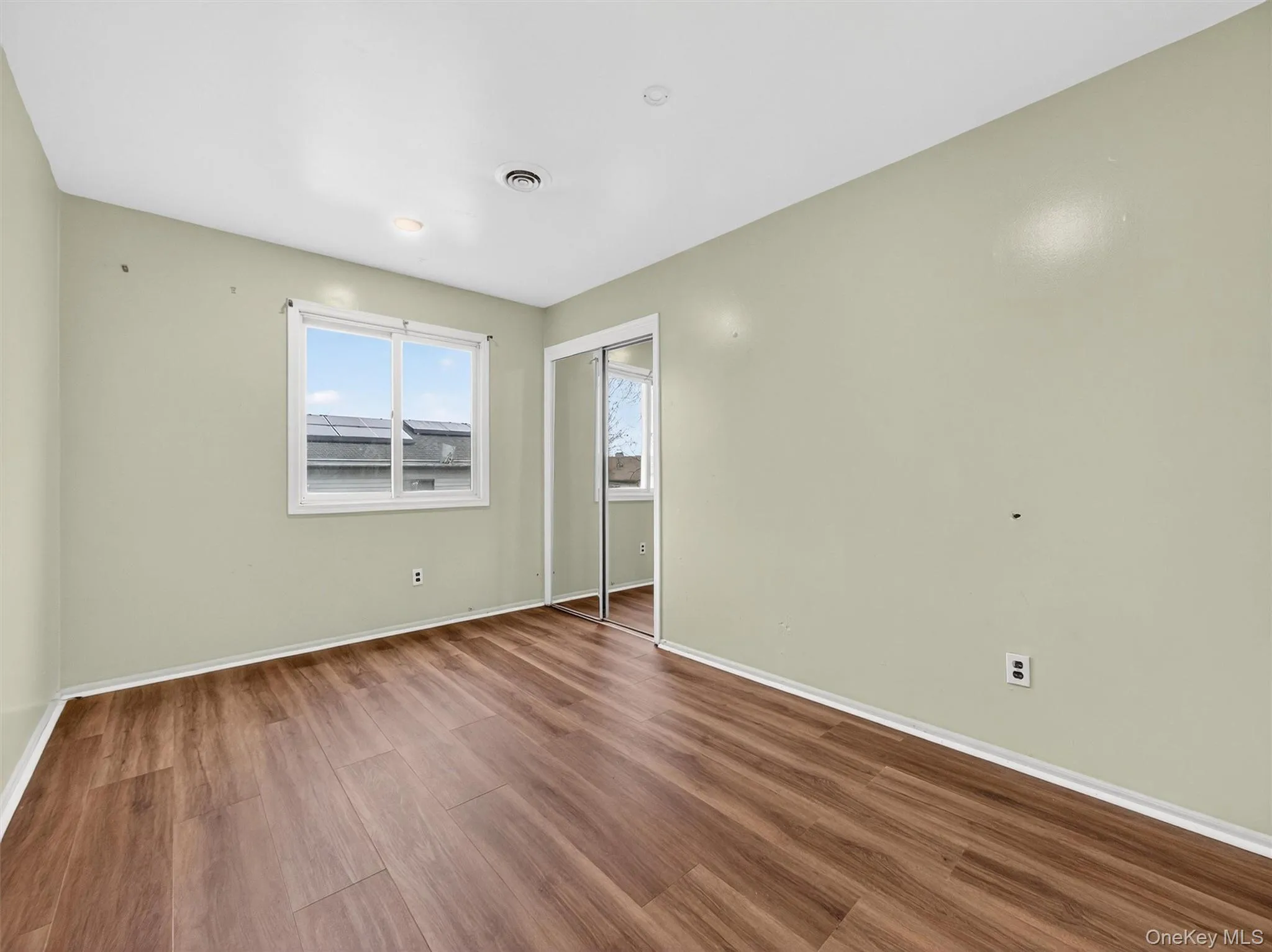 Unfurnished bedroom featuring wood finished floors and a closet Unfurnished bedroom featuring wood finished floors and a closet