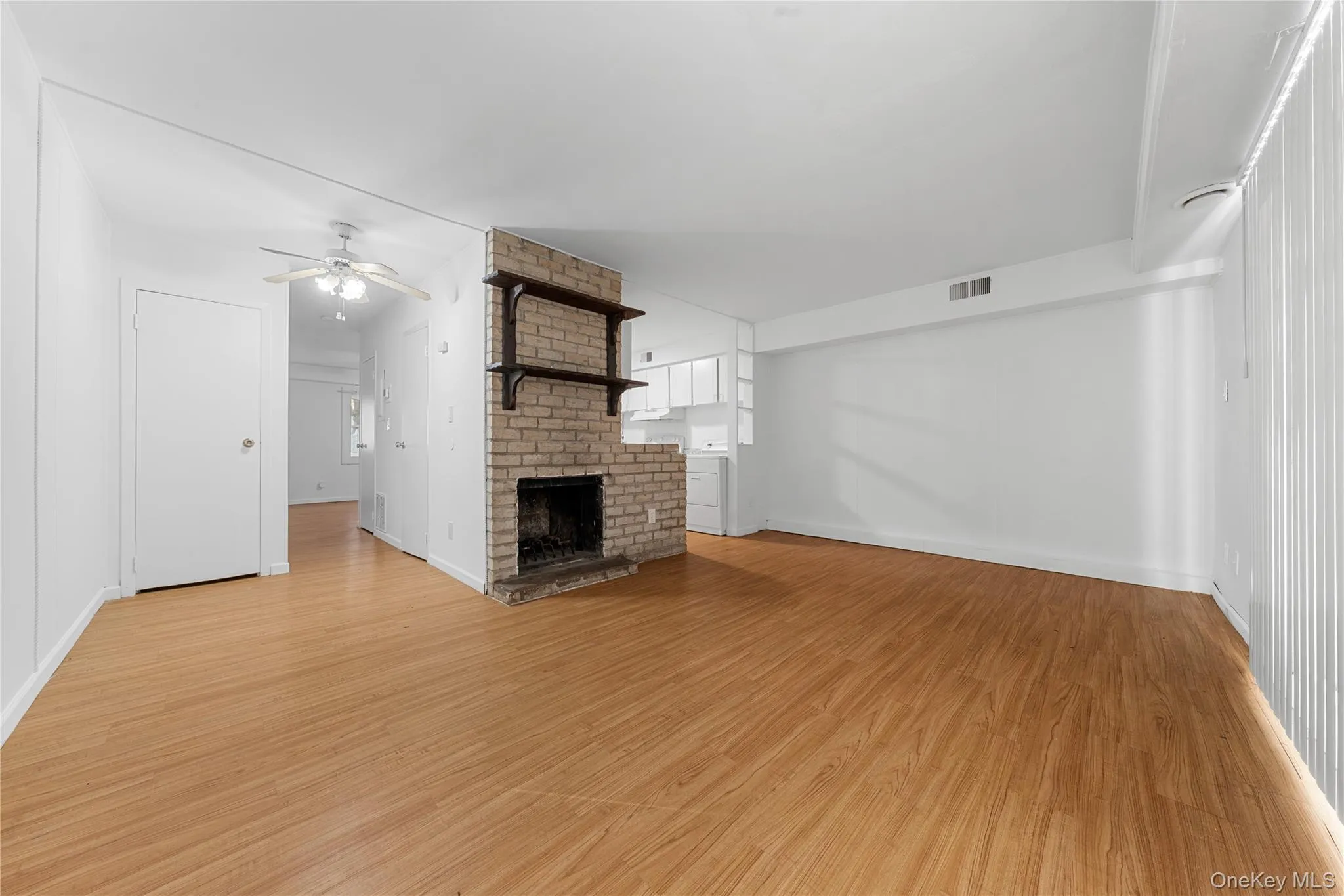 Unfurnished living room with light wood-style floors, a brick fireplace, and ceiling fan Unfurnished living room with light wood-style floors, a brick fireplace, and ceiling fan
