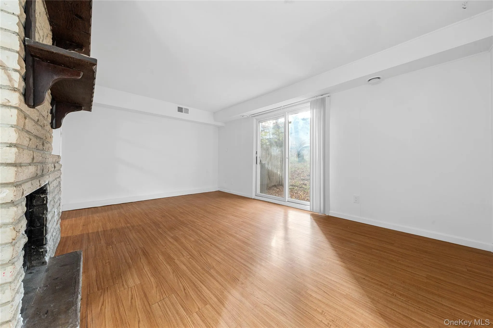 Unfurnished living room featuring light wood-style flooring and a fireplace Unfurnished living room featuring light wood-style flooring and a fireplace