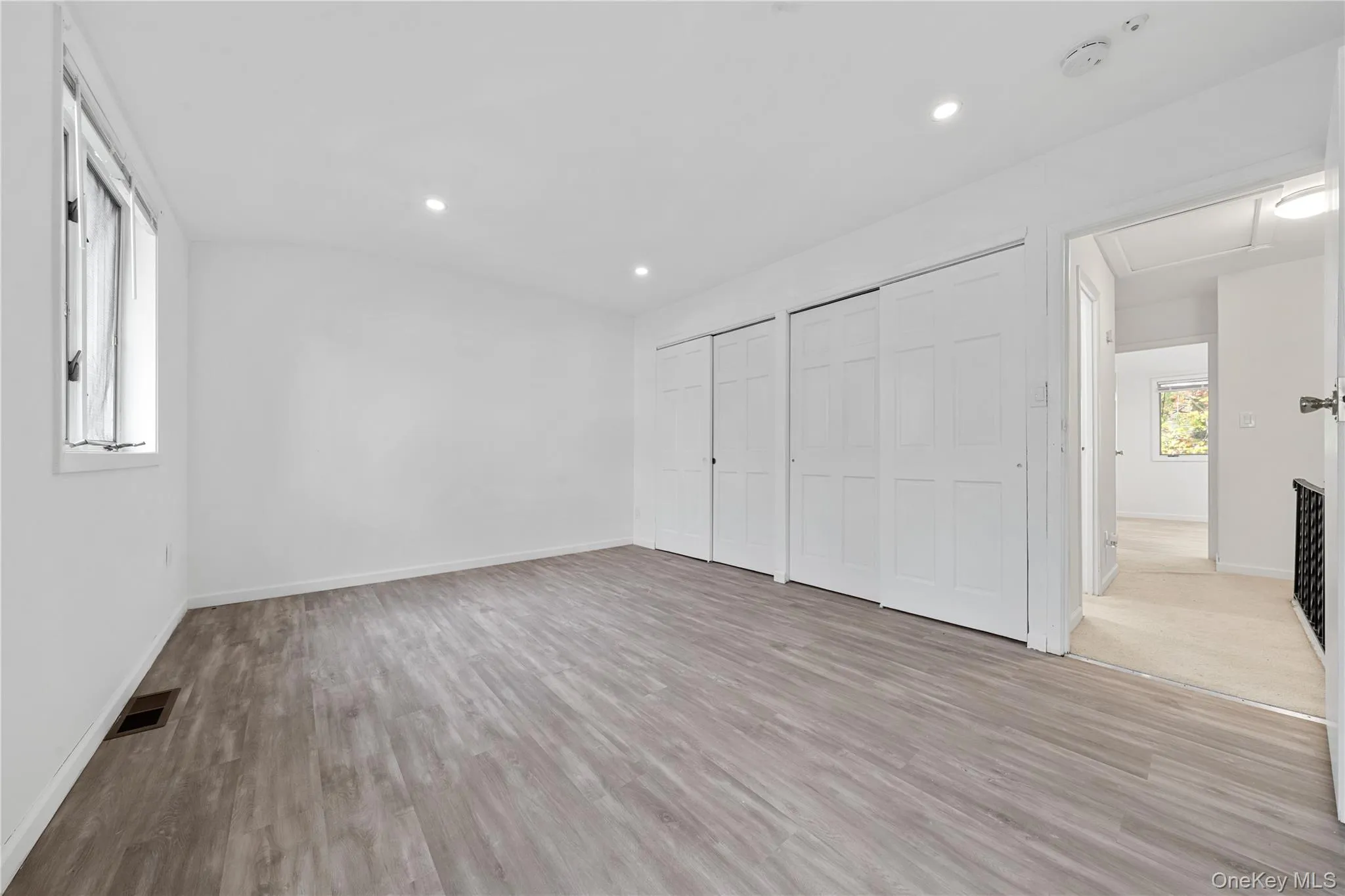 Unfurnished bedroom featuring two closets, light wood finished floors, recessed lighting, and attic access Unfurnished bedroom featuring two closets, light wood finished floors, recessed lighting, and attic access