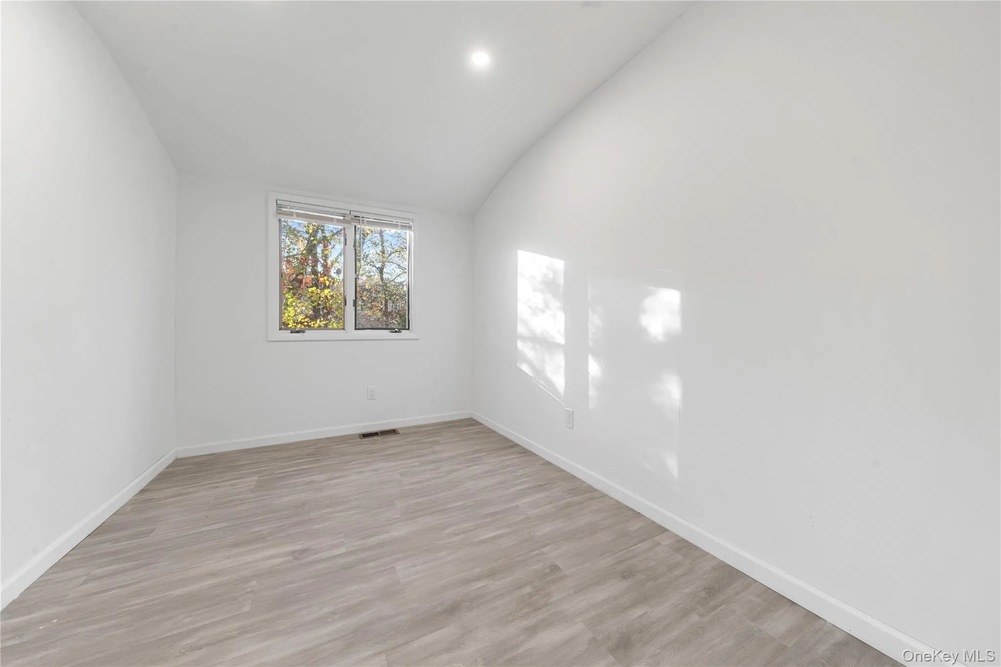 Spare room featuring lofted ceiling, light wood-type flooring, and recessed lighting Spare room featuring lofted ceiling, light wood-type flooring, and recessed lighting