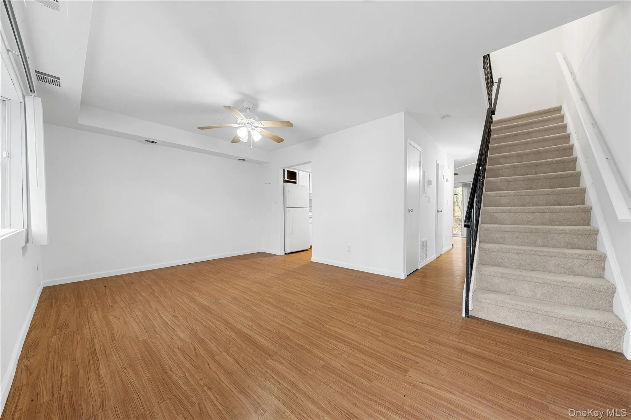 Unfurnished living room with light wood-style floors, ceiling fan, and stairway Unfurnished living room with light wood-style floors, ceiling fan, and stairway