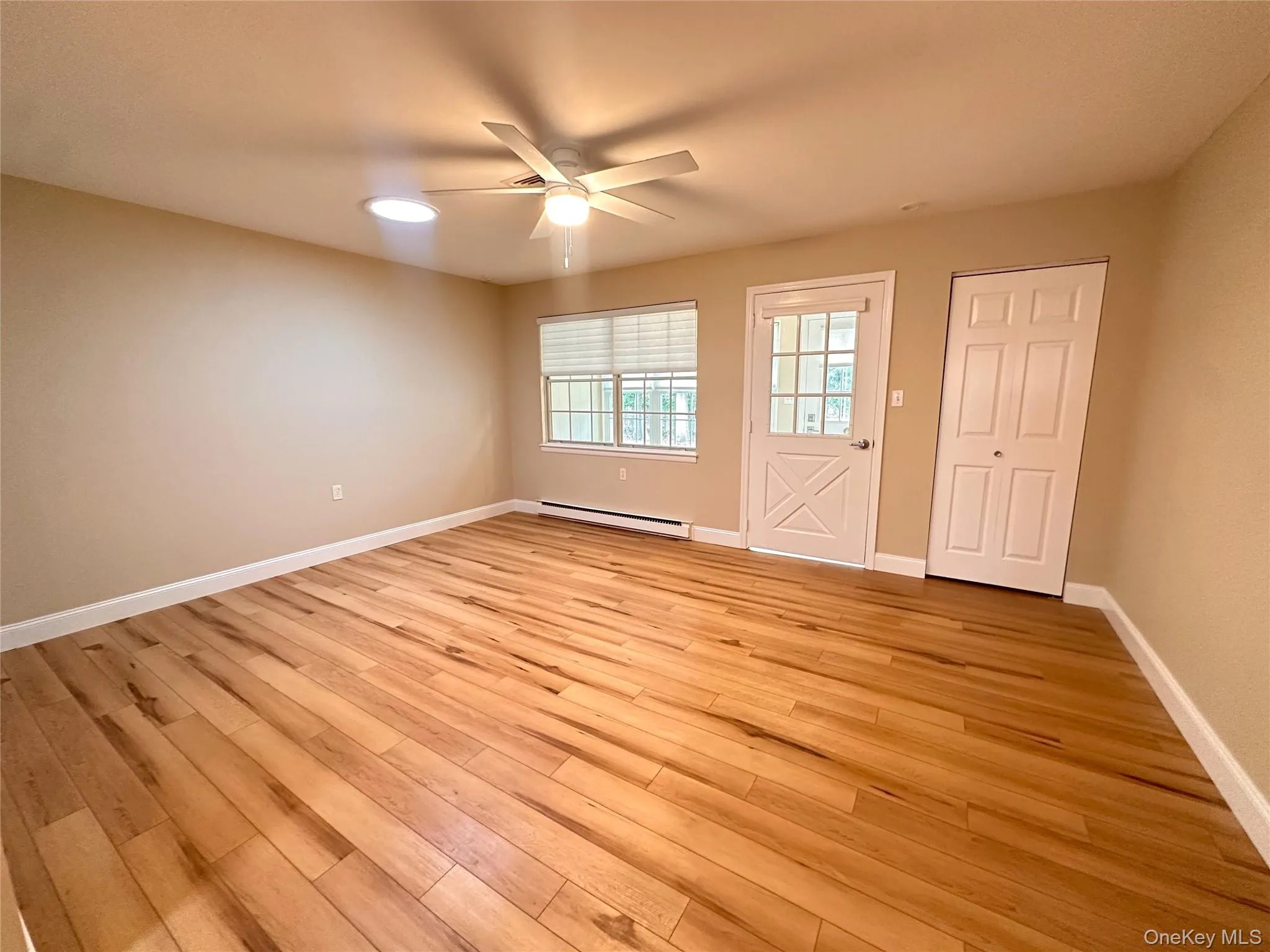 Spare room featuring a baseboard radiator, ceiling fan, and light wood-style flooring Spare room featuring a baseboard radiator, ceiling fan, and light wood-style flooring