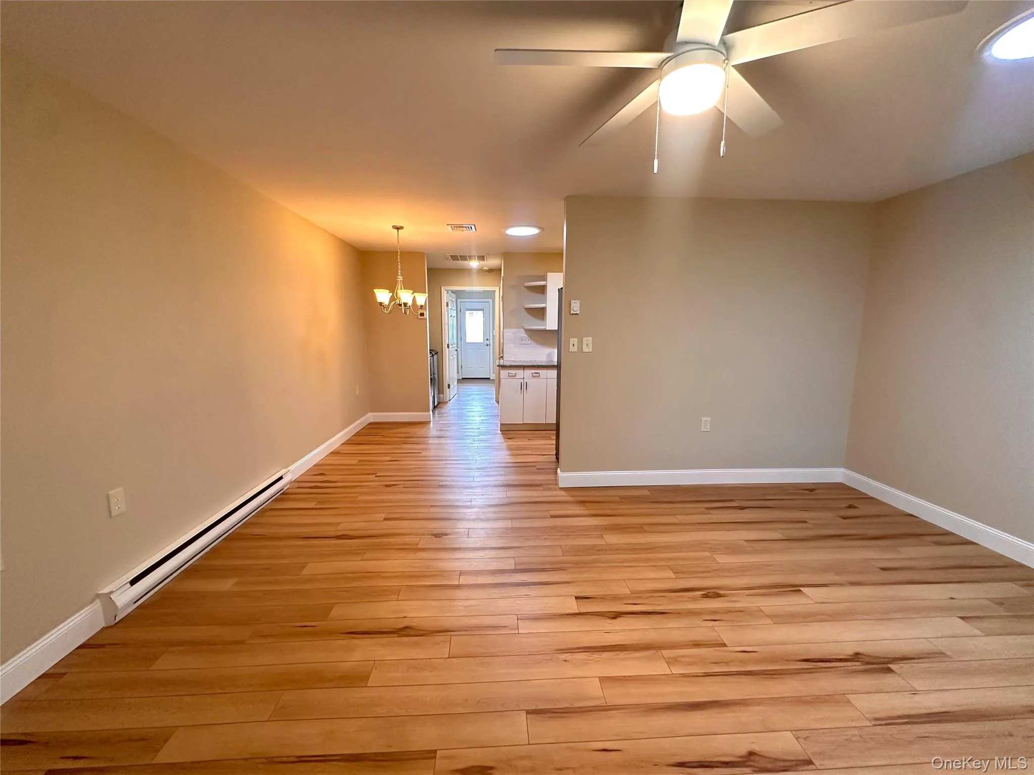 Unfurnished room featuring a baseboard heating unit, a chandelier, light wood-style flooring, and ceiling fan Unfurnished room featuring a baseboard heating unit, a chandelier, light wood-style flooring, and ceiling fan