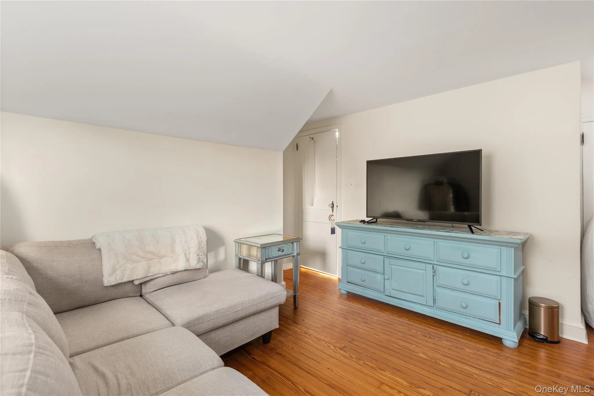 Living area featuring vaulted ceiling and light wood-style flooring Living area featuring vaulted ceiling and light wood-style flooring