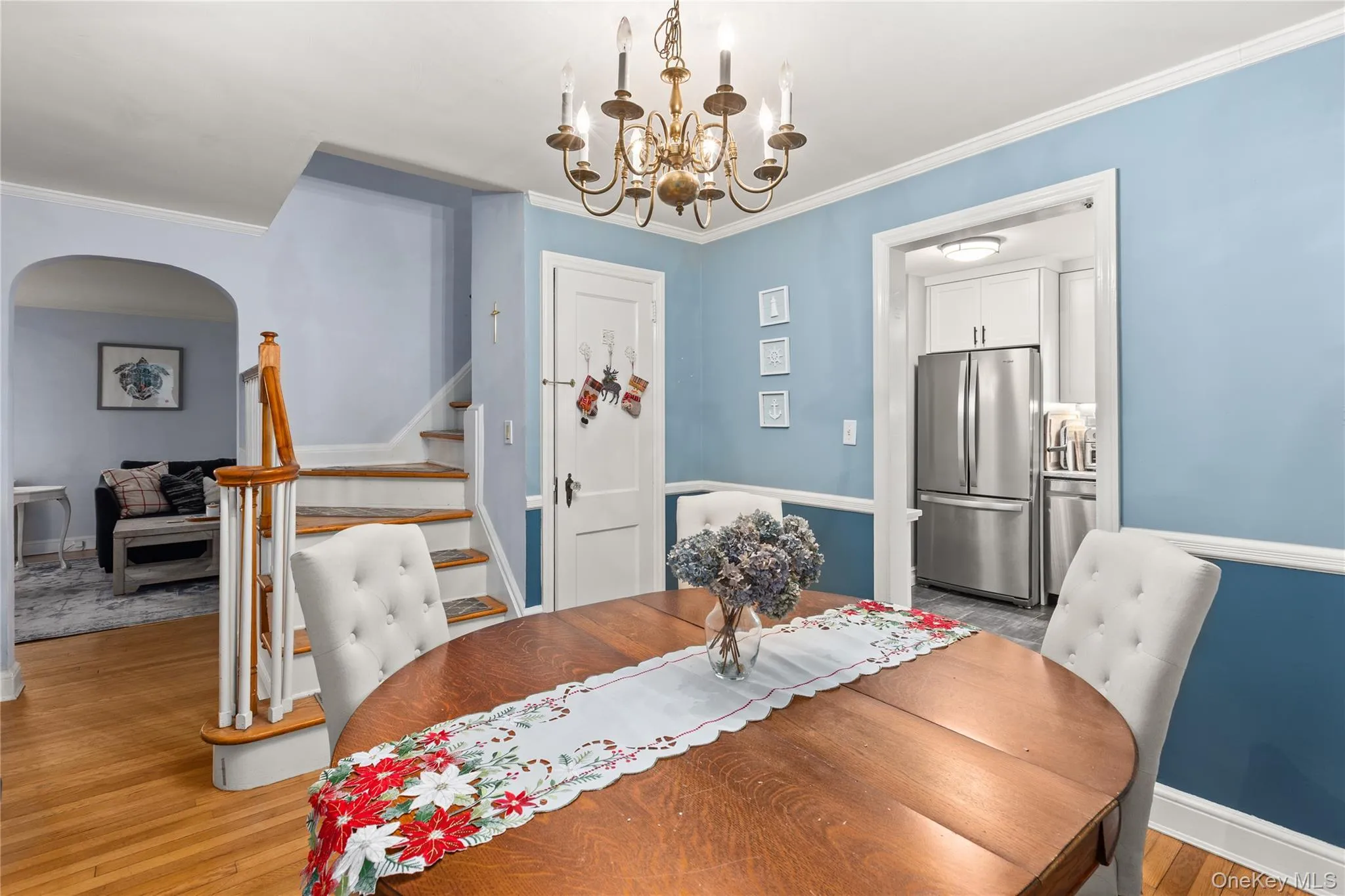 Dining space featuring a chandelier, stairs, ornamental molding, light wood-style floors, and arched walkways Dining space featuring a chandelier, stairs, ornamental molding, light wood-style floors, and arched walkways