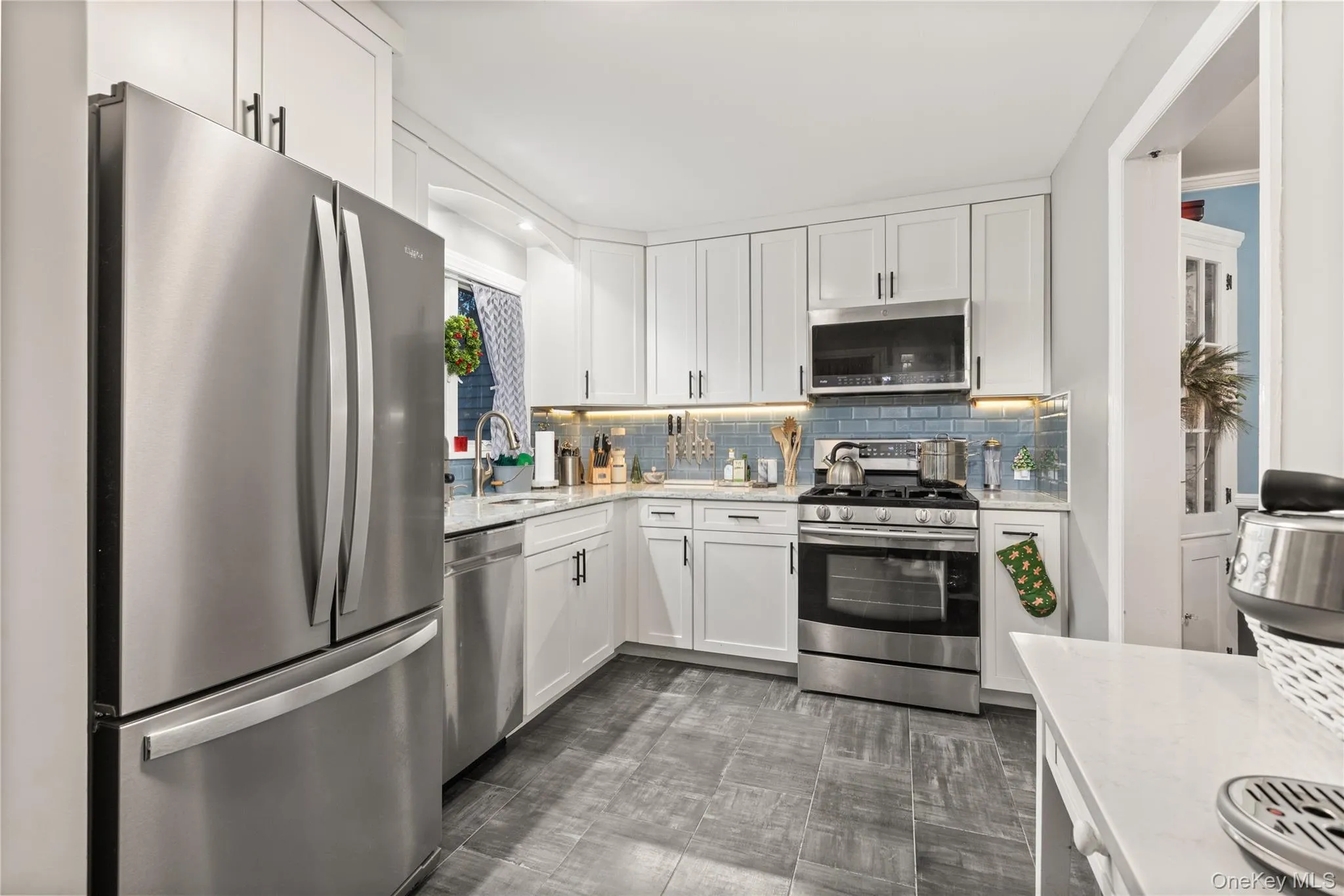 Kitchen with appliances with stainless steel finishes, white cabinetry, and light stone countertops Kitchen with appliances with stainless steel finishes, white cabinetry, and light stone countertops