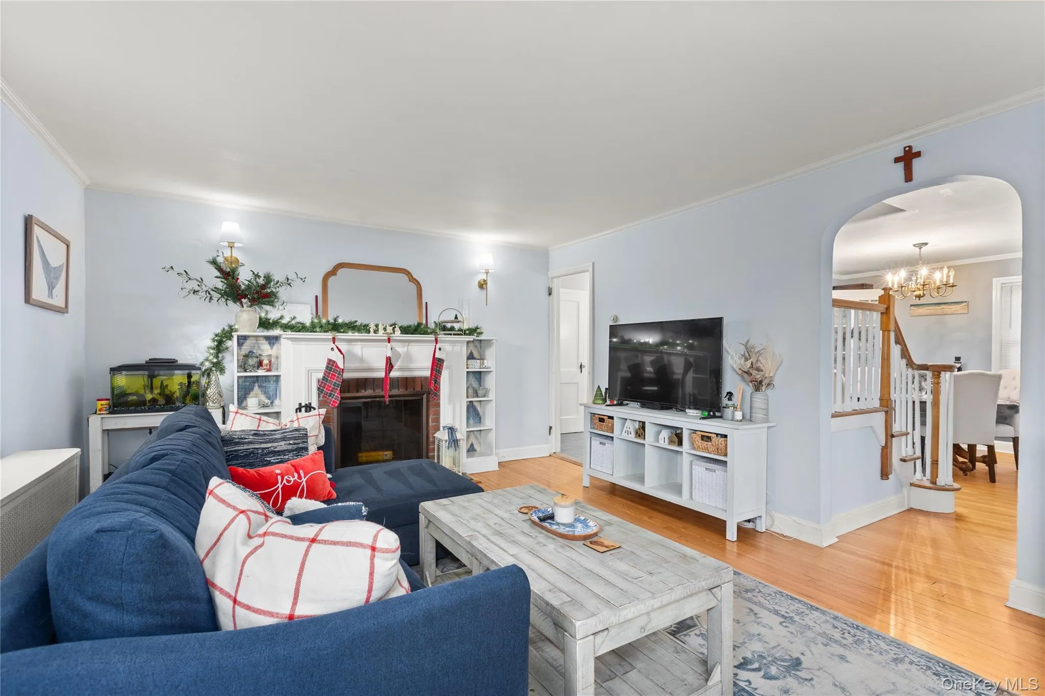 Living room with crown molding, arched walkways, a chandelier, a fireplace, and wood finished floors Living room with crown molding, arched walkways, a chandelier, a fireplace, and wood finished floors