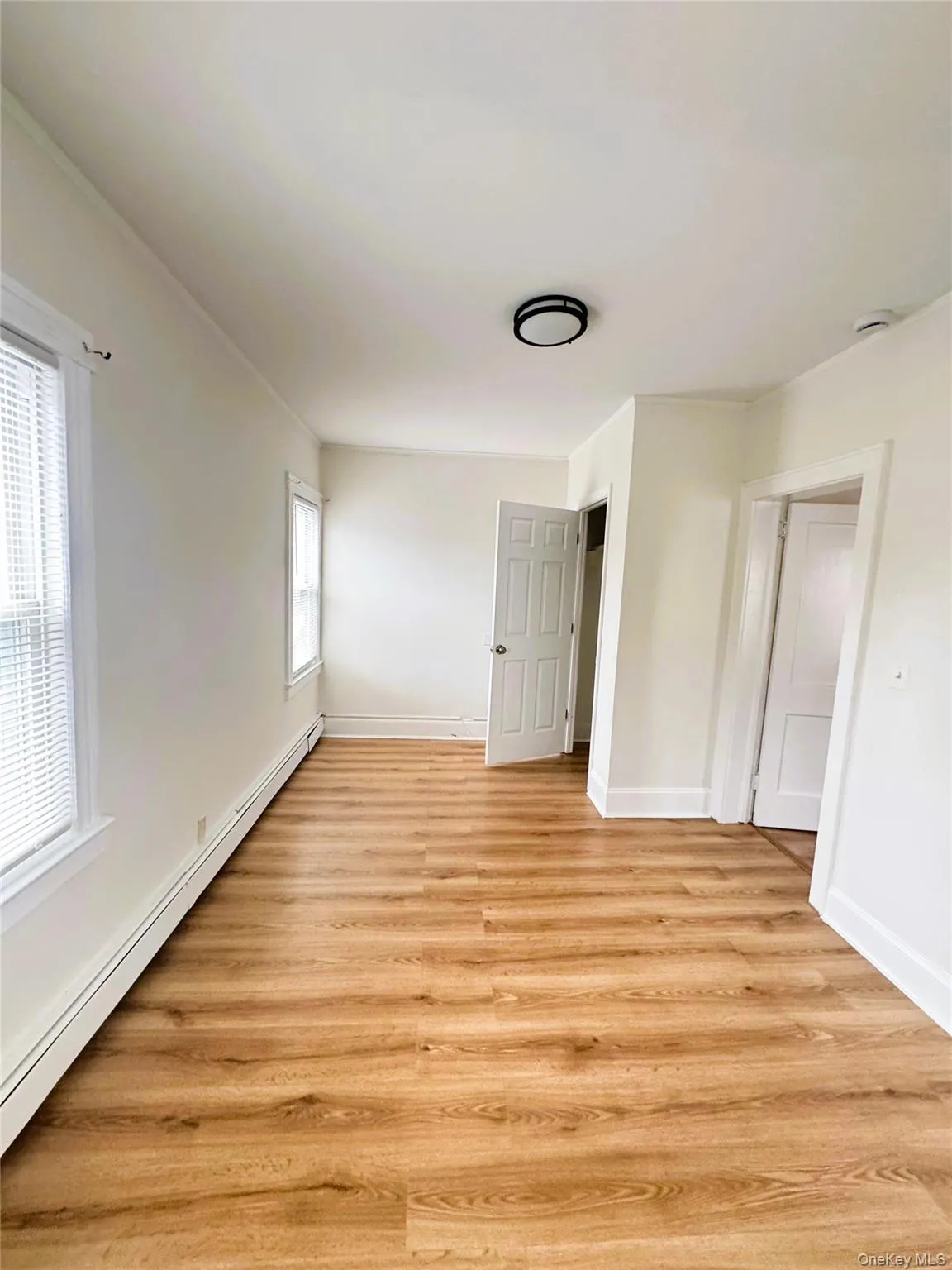 Unfurnished bedroom with baseboard heating and light wood-type flooring Unfurnished bedroom with baseboard heating and light wood-type flooring