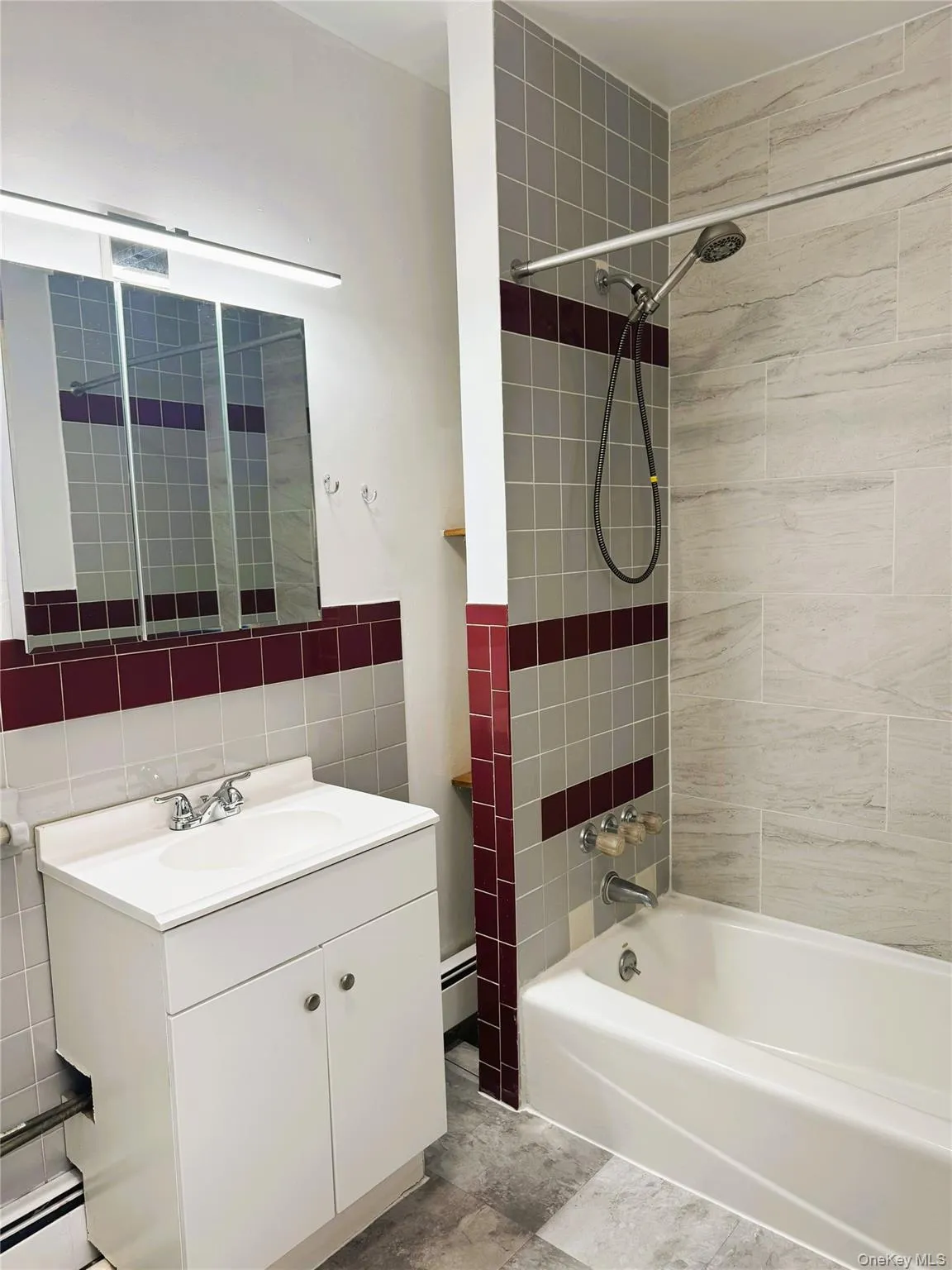 Bathroom with vanity, shower / tub combination, a baseboard heating unit, tile walls, and baseboard heating Bathroom with vanity, shower / tub combination, a baseboard heating unit, tile walls, and baseboard heating