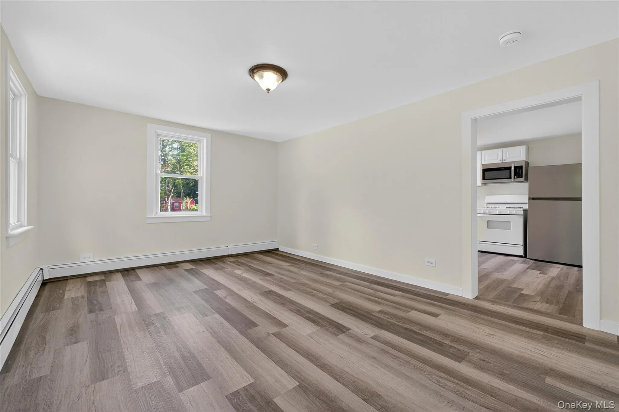 Empty room featuring light wood finished floors, baseboard heating, and a baseboard radiator Empty room featuring light wood finished floors, baseboard heating, and a baseboard radiator