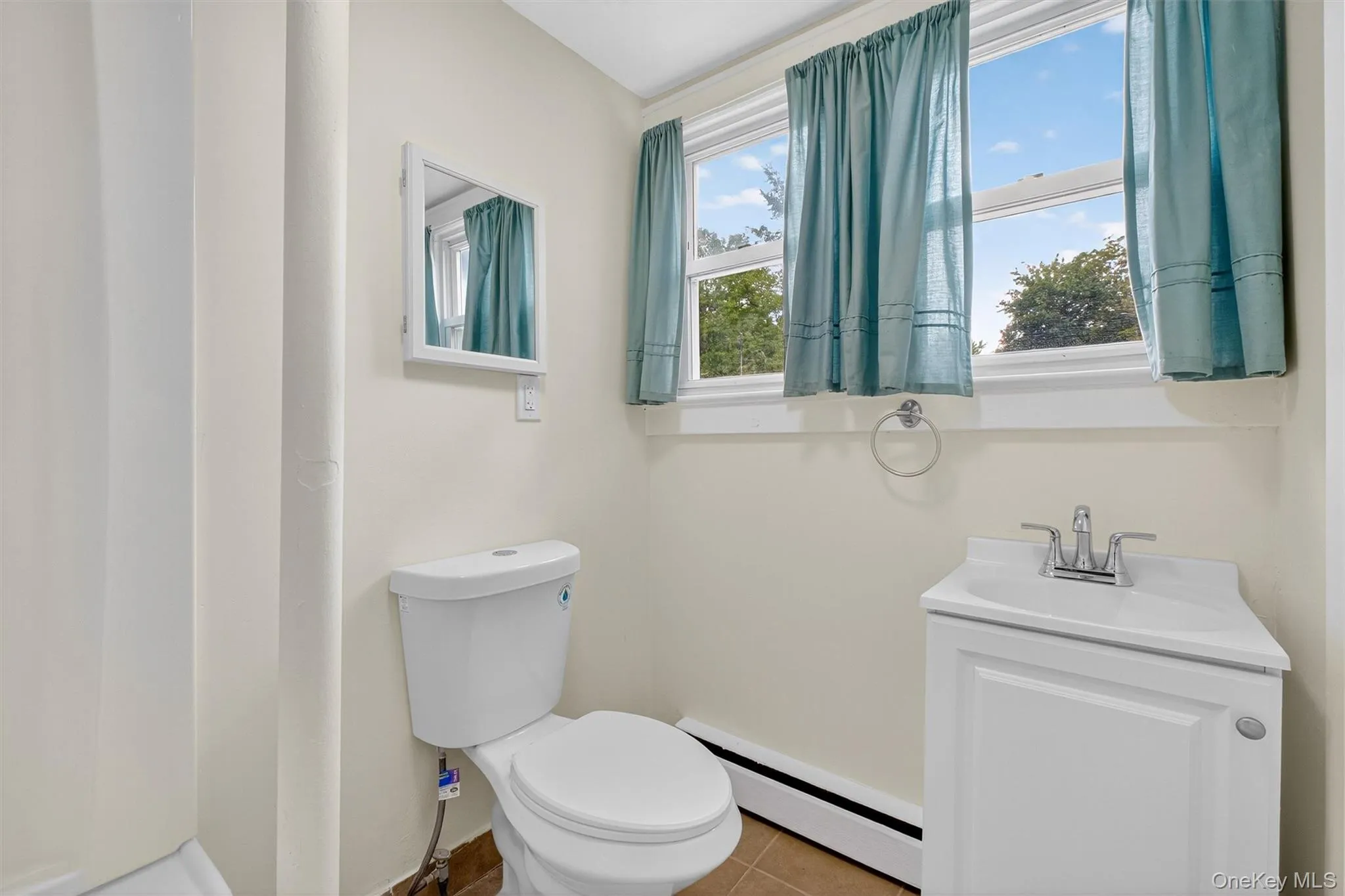 Half bathroom with a baseboard heating unit, tile patterned flooring, and vanity Half bathroom with a baseboard heating unit, tile patterned flooring, and vanity