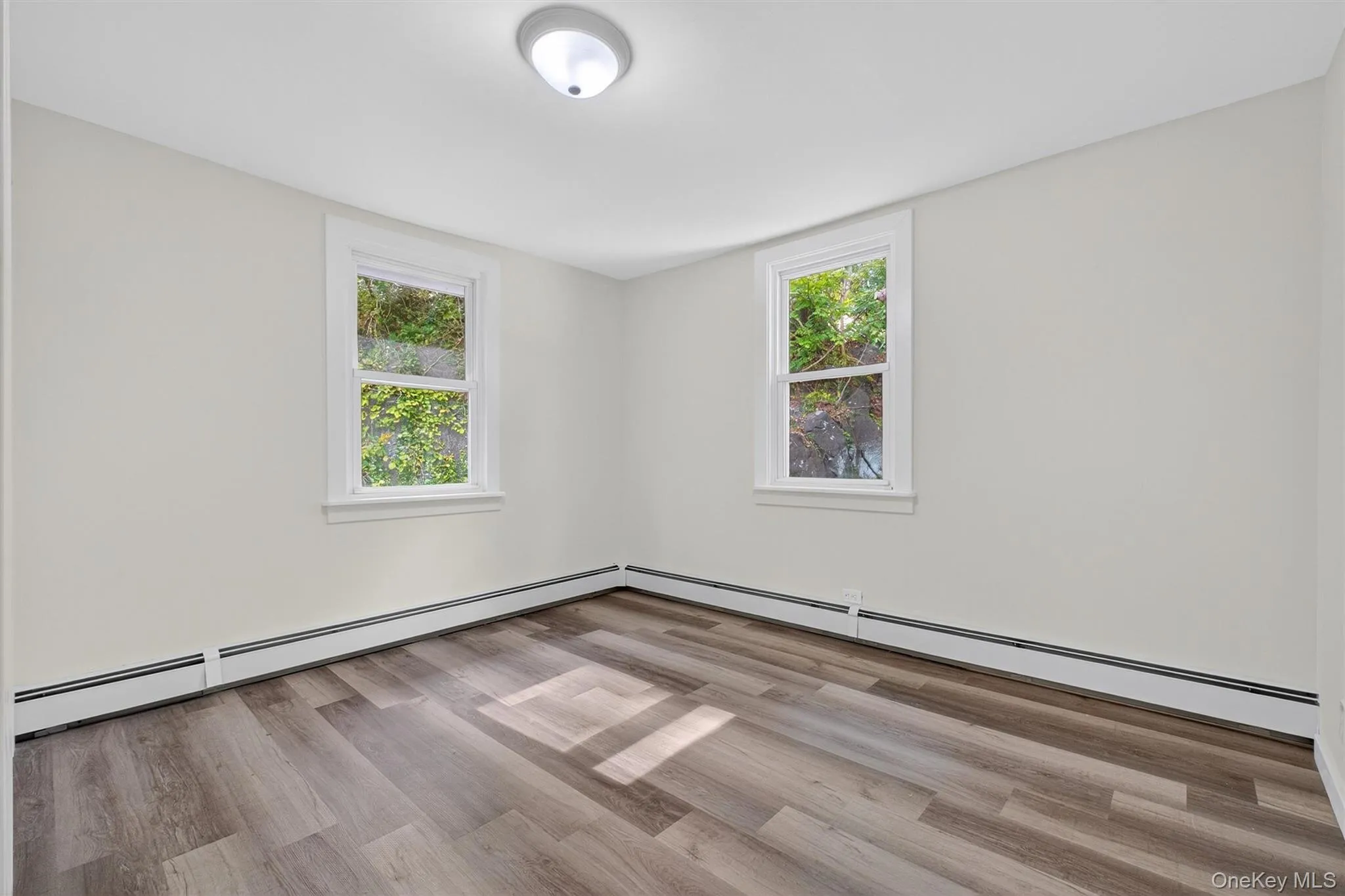 Unfurnished room featuring baseboard heating and light wood finished floors Unfurnished room featuring baseboard heating and light wood finished floors