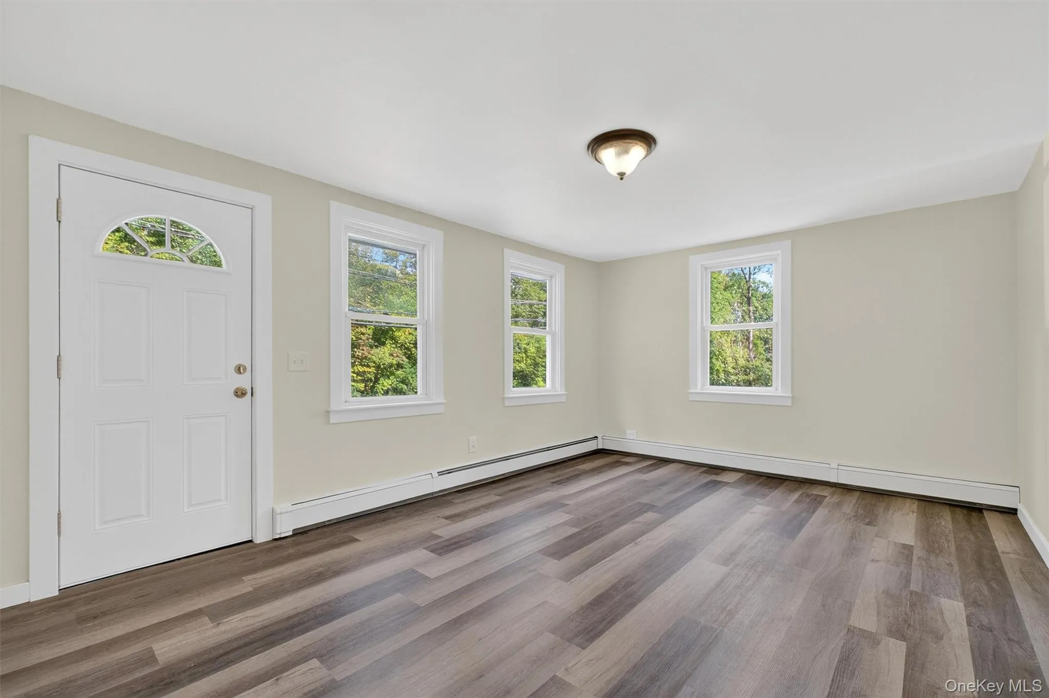 Foyer with light wood-style flooring, a baseboard heating unit, and a baseboard radiator Foyer with light wood-style flooring, a baseboard heating unit, and a baseboard radiator