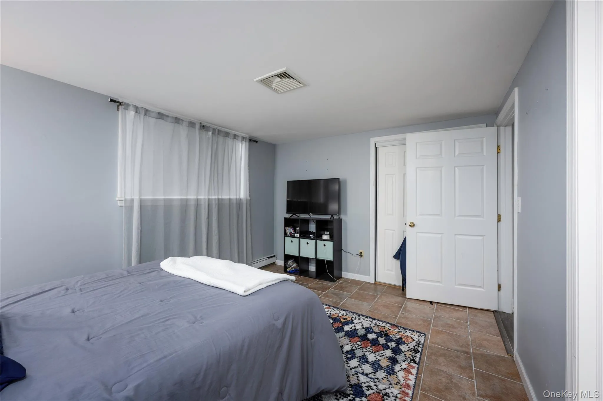 Tiled bedroom with baseboards and a baseboard radiator Tiled bedroom with baseboards and a baseboard radiator