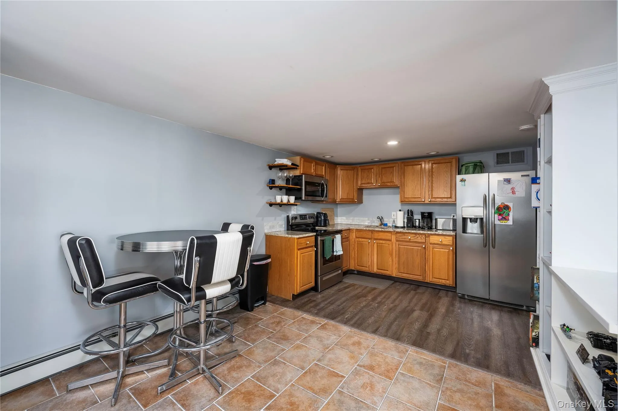 Kitchen featuring brown cabinets, a baseboard heating unit, appliances with stainless steel finishes, open shelves, and recessed lighting Kitchen featuring brown cabinets, a baseboard heating unit, appliances with stainless steel finishes, open shelves, and recessed lighting