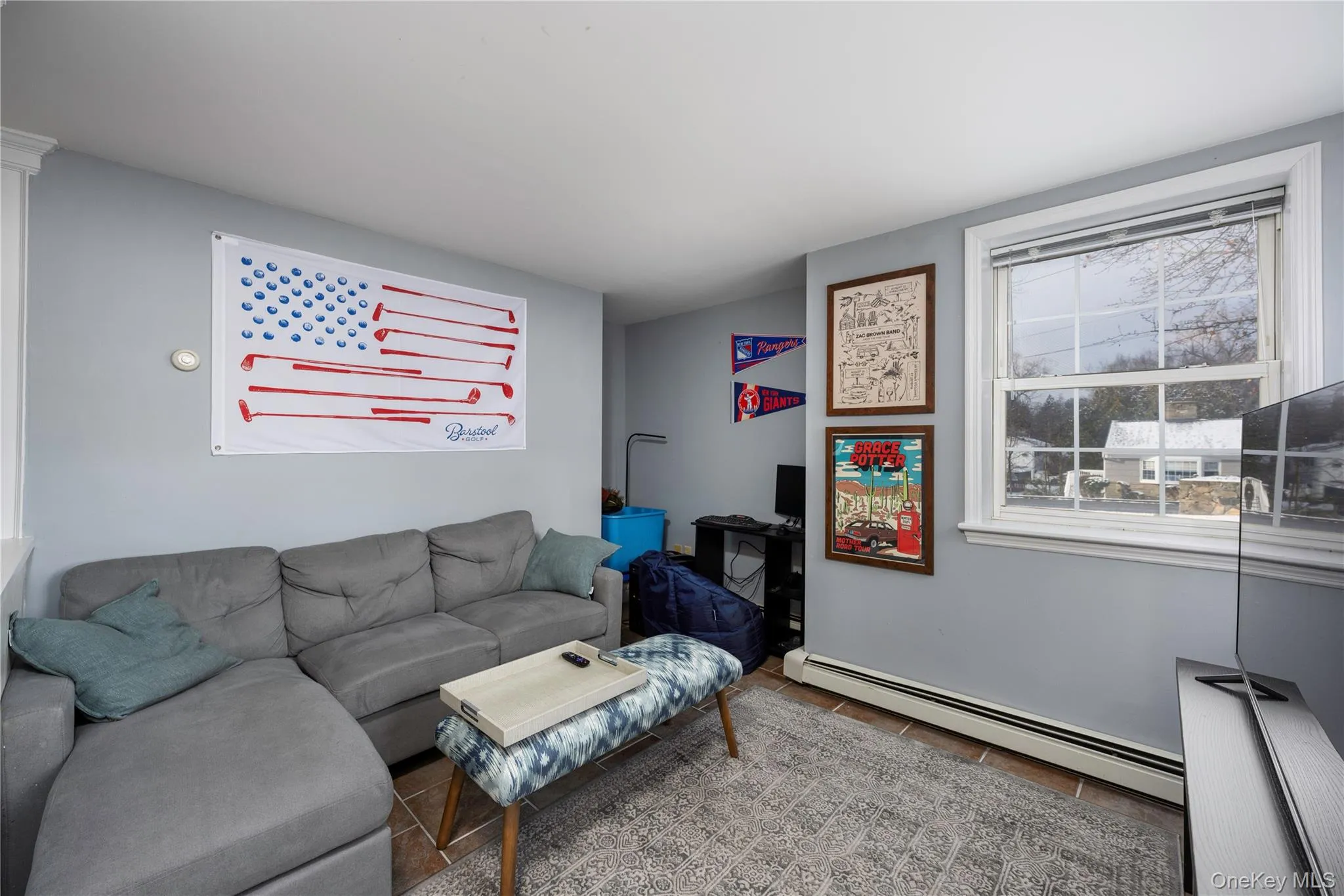 Living room featuring a baseboard heating unit, healthy amount of natural light, and tile patterned flooring Living room featuring a baseboard heating unit, healthy amount of natural light, and tile patterned flooring