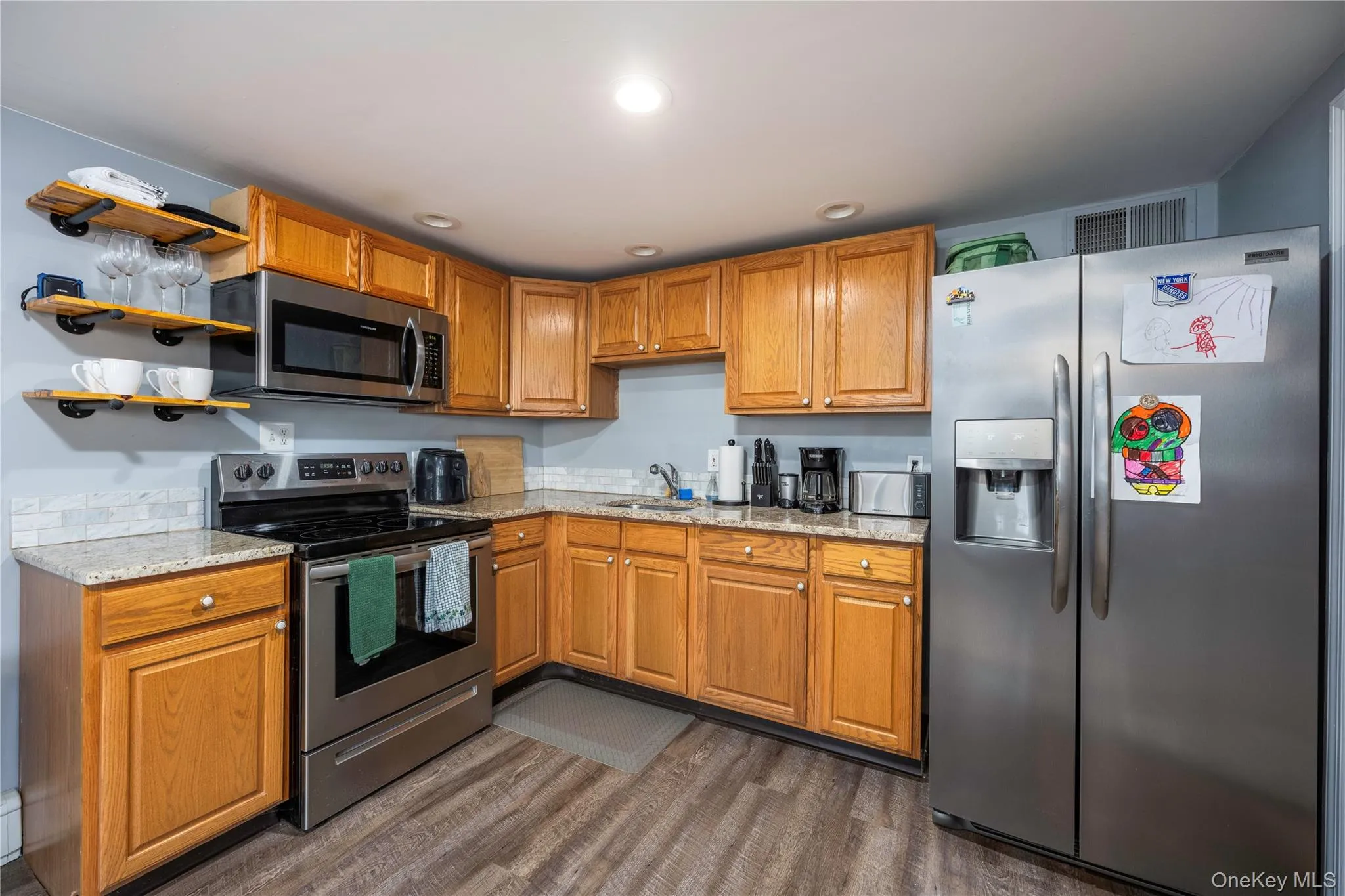 Kitchen featuring stainless steel appliances, dark wood-style flooring, open shelves, brown cabinets, and recessed lighting Kitchen featuring stainless steel appliances, dark wood-style flooring, open shelves, brown cabinets, and recessed lighting
