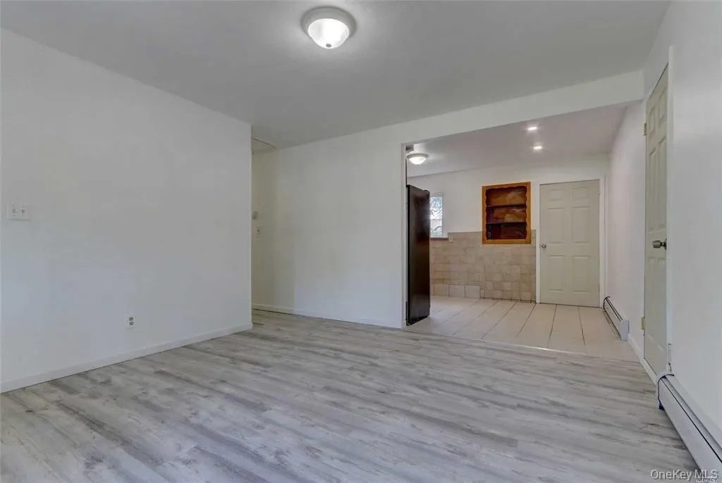 Empty room featuring a baseboard heating unit and light wood-style floors Empty room featuring a baseboard heating unit and light wood-style floors