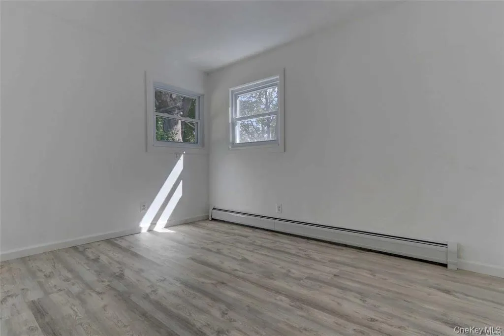 Empty room with a baseboard radiator and light wood finished floors Empty room with a baseboard radiator and light wood finished floors