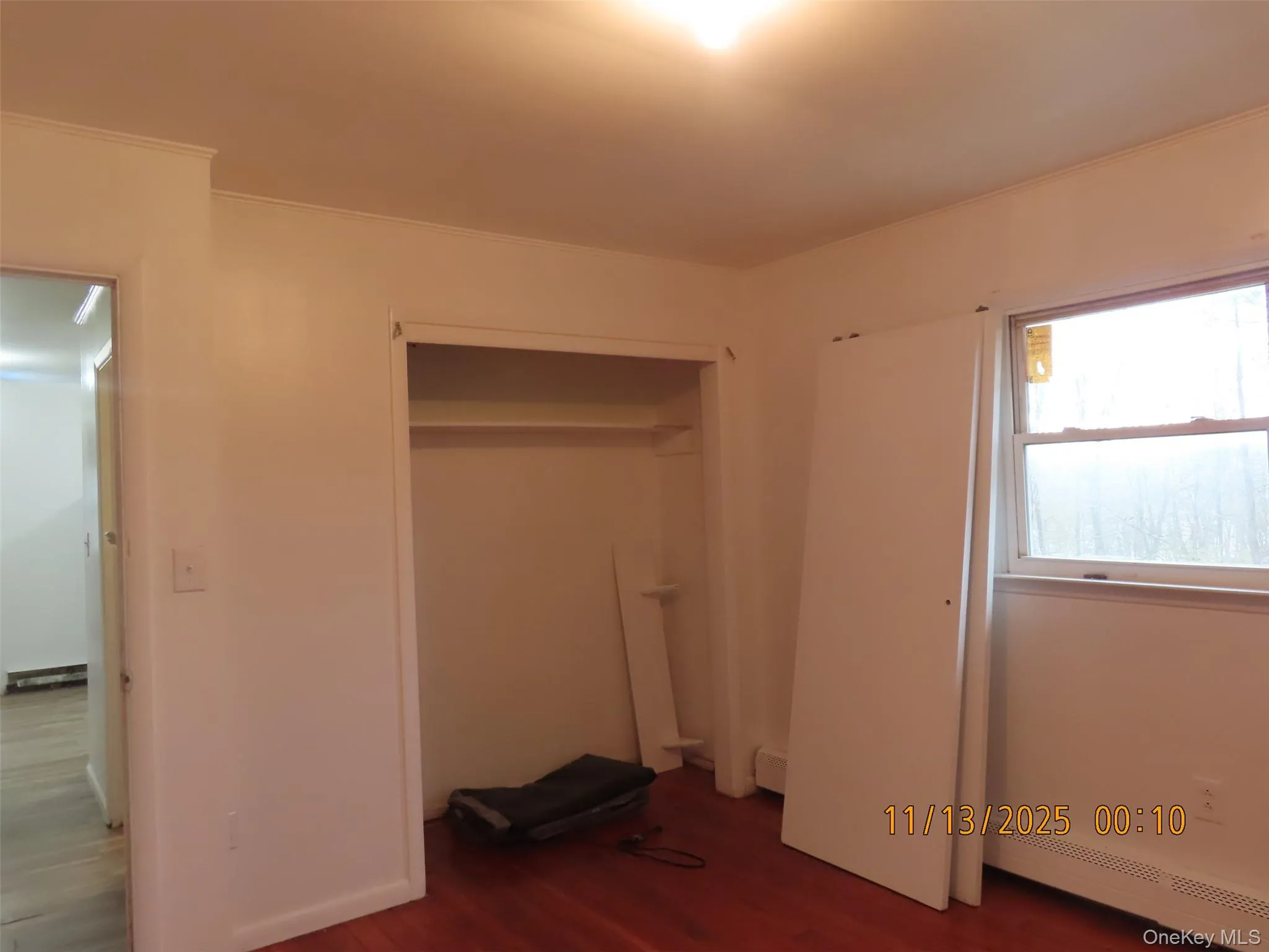 Unfurnished bedroom with dark wood finished floors, a closet, a baseboard radiator, and crown molding Unfurnished bedroom with dark wood finished floors, a closet, a baseboard radiator, and crown molding