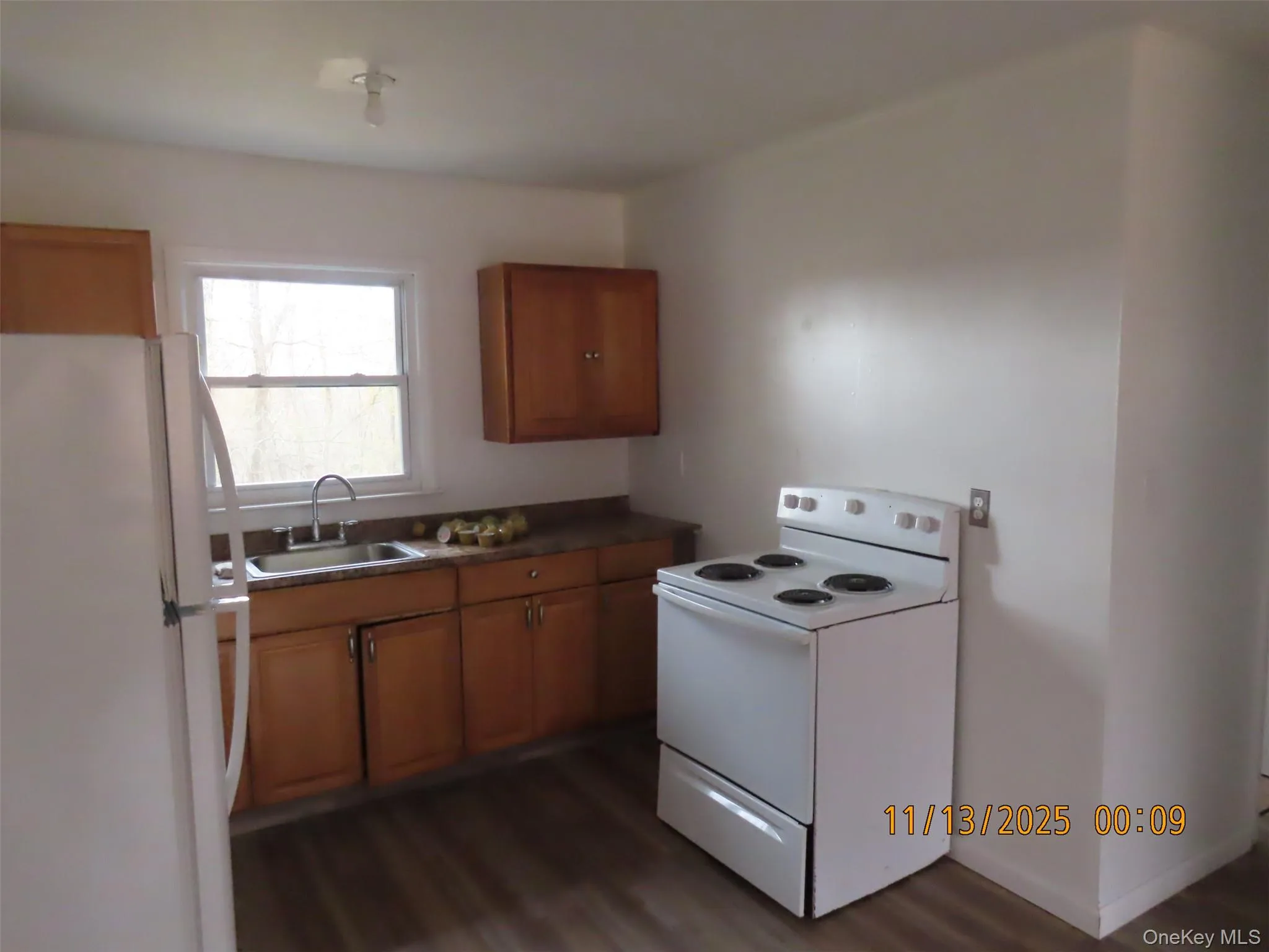 Kitchen featuring white appliances, brown cabinetry, and dark wood-style flooring Kitchen featuring white appliances, brown cabinetry, and dark wood-style flooring