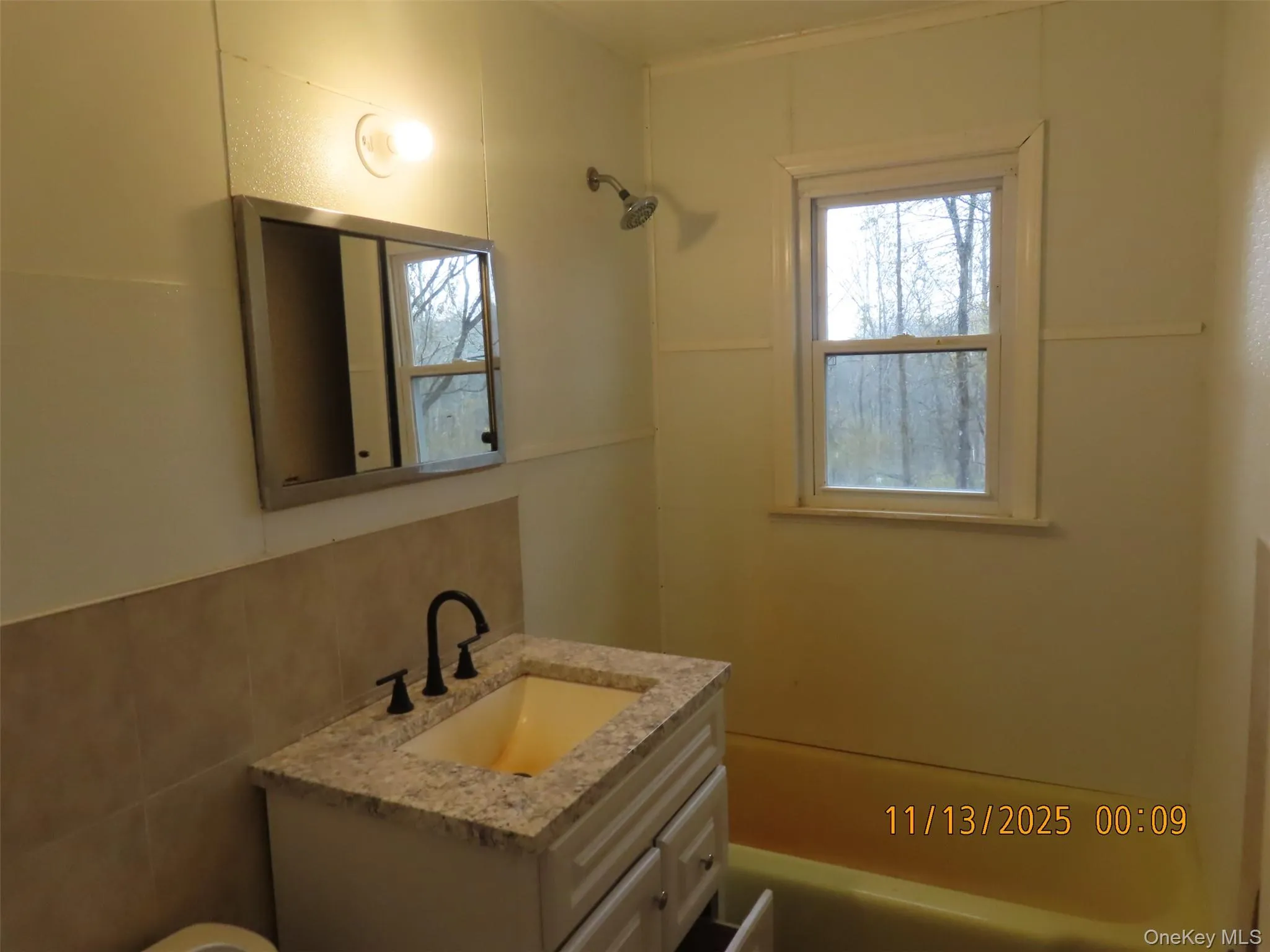 Bathroom with vanity, shower / tub combination, and tile walls Bathroom with vanity, shower / tub combination, and tile walls