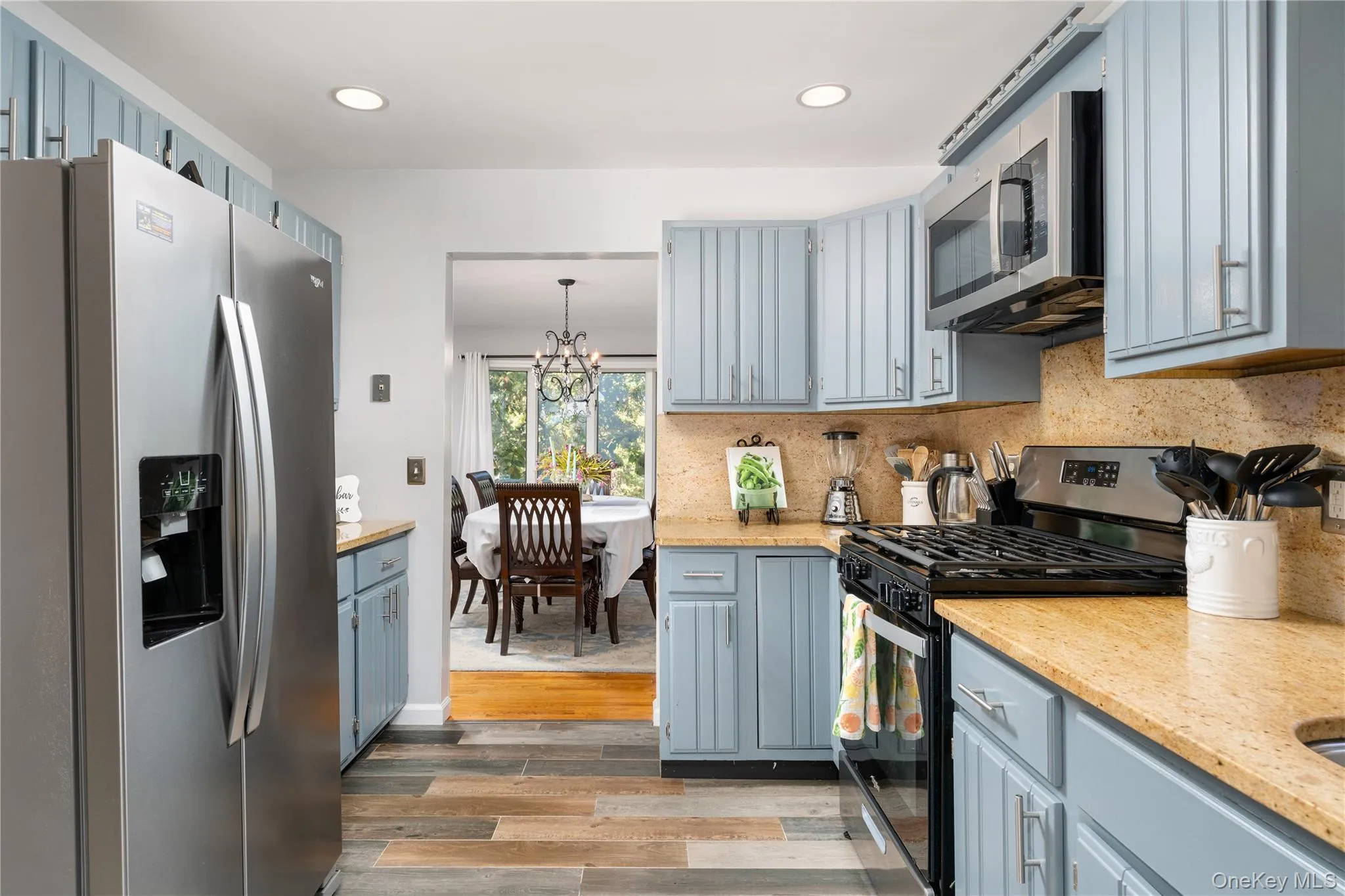 Kitchen featuring stainless steel appliances, light wood-style flooring, a chandelier, recessed lighting, and tasteful backsplash Kitchen featuring stainless steel appliances, light wood-style flooring, a chandelier, recessed lighting, and tasteful backsplash