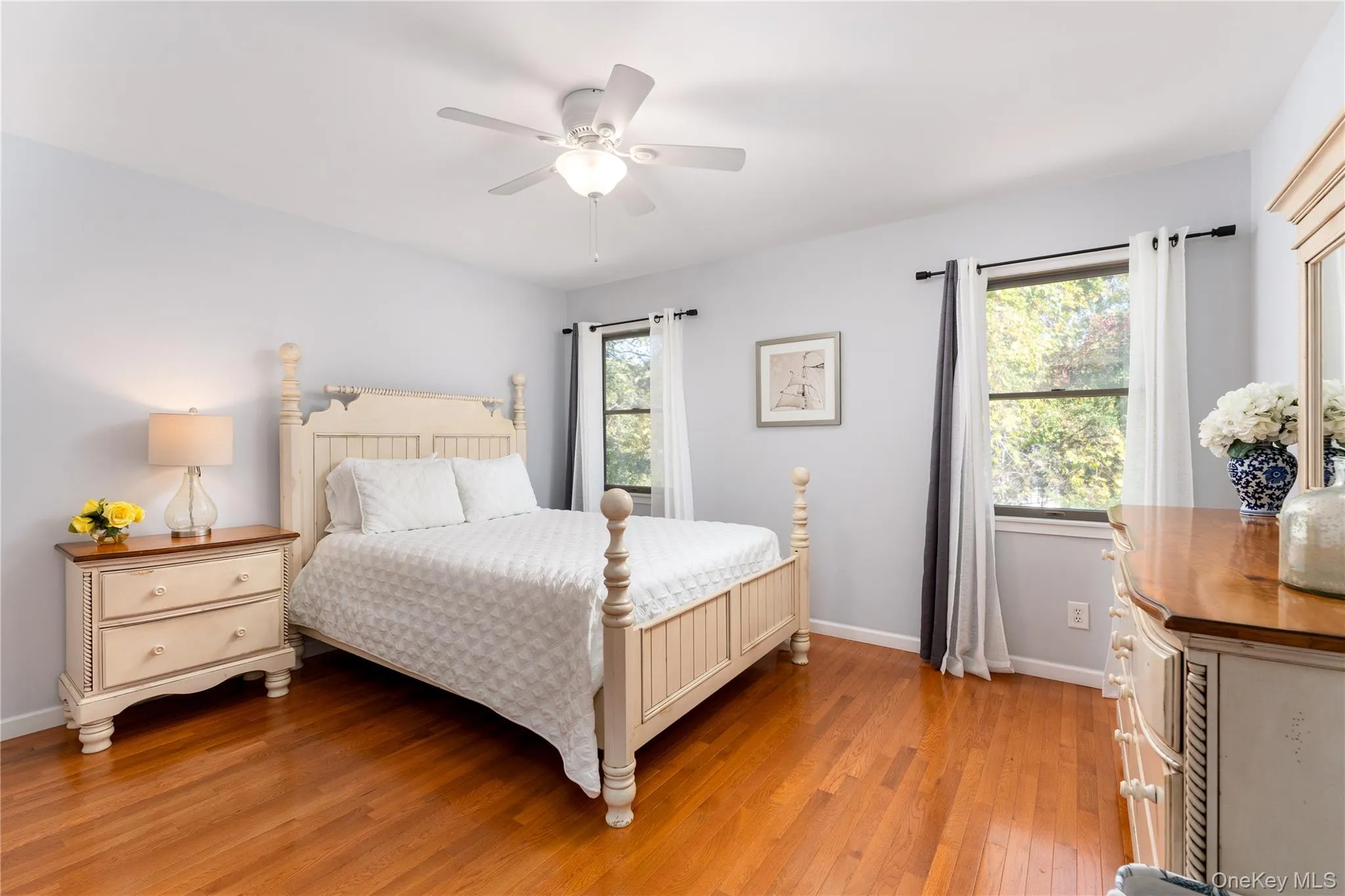 Bedroom featuring light wood-type flooring, multiple windows, and a ceiling fan Bedroom featuring light wood-type flooring, multiple windows, and a ceiling fan