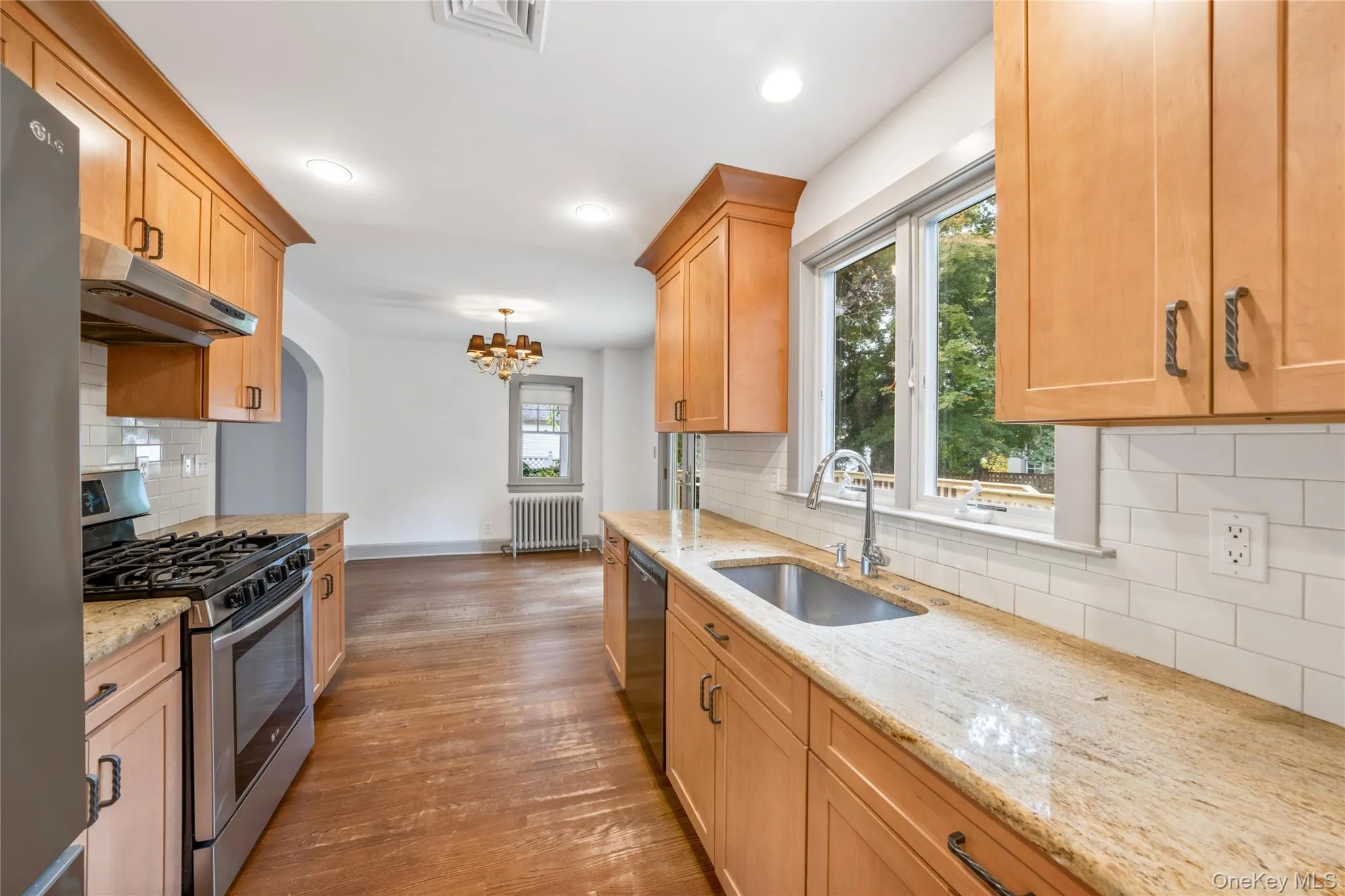 Kitchen featuring stainless steel appliances, backsplash, light stone counters, under cabinet range hood, and recessed lighting Kitchen featuring stainless steel appliances, backsplash, light stone counters, under cabinet range hood, and recessed lighting